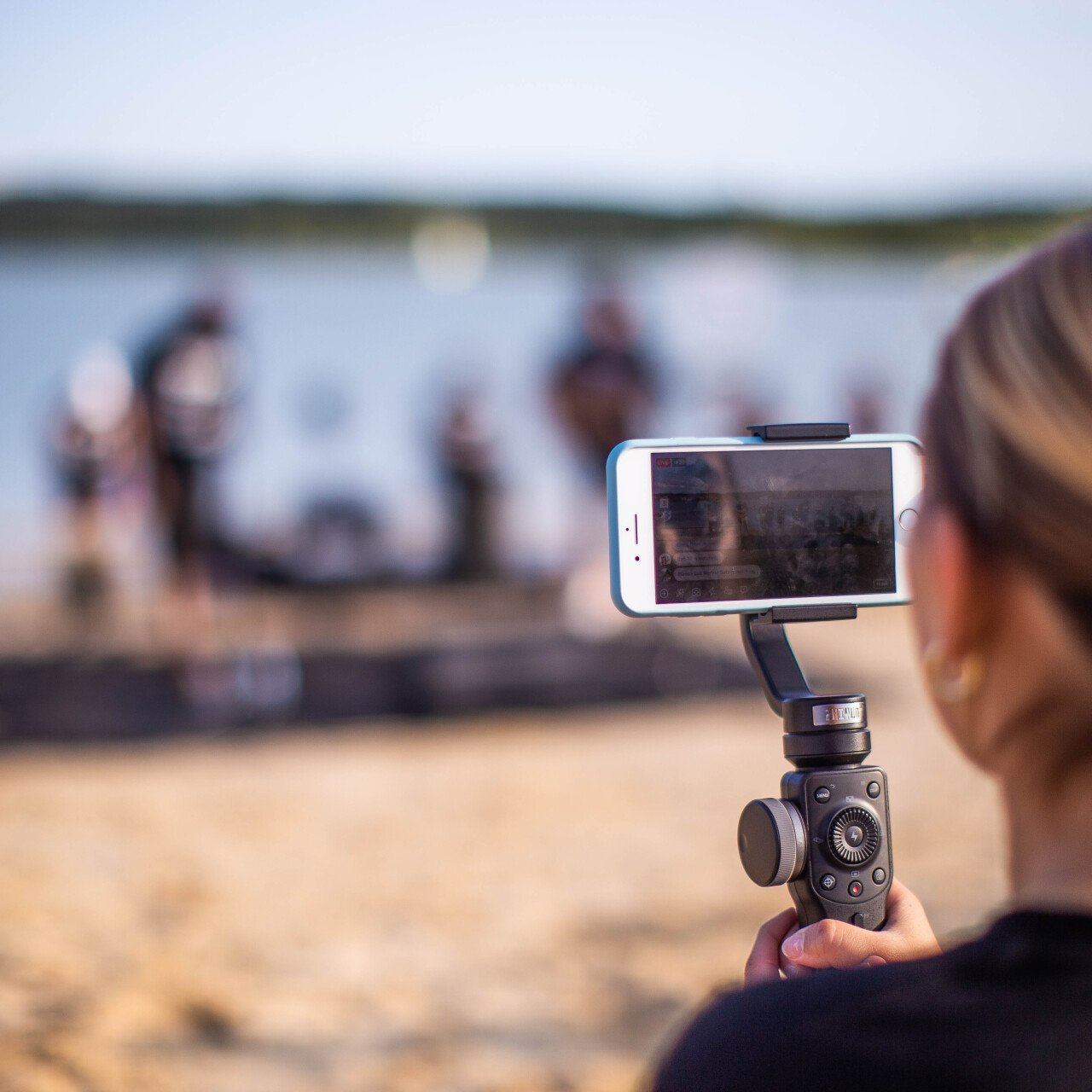 A woman is taking a picture with a cell phone on a tripod