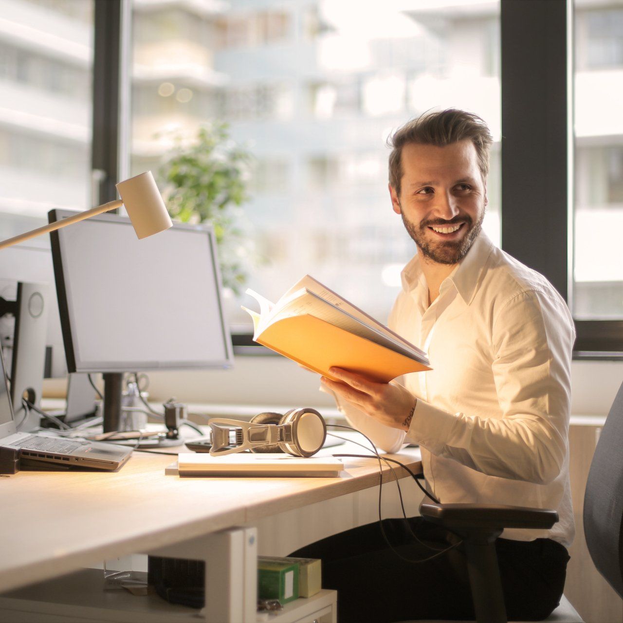 A man is sitting at a desk reading a book