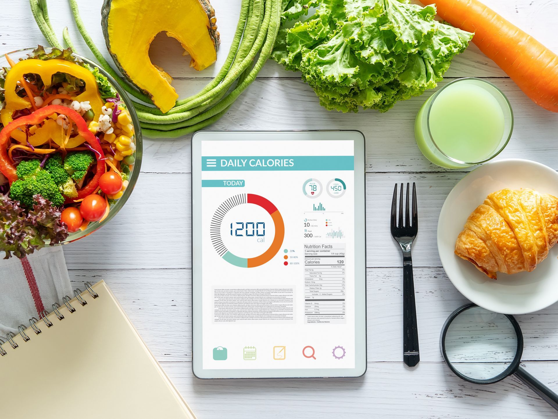 Tablet displaying nutrition information surrounded by healthy food items.
