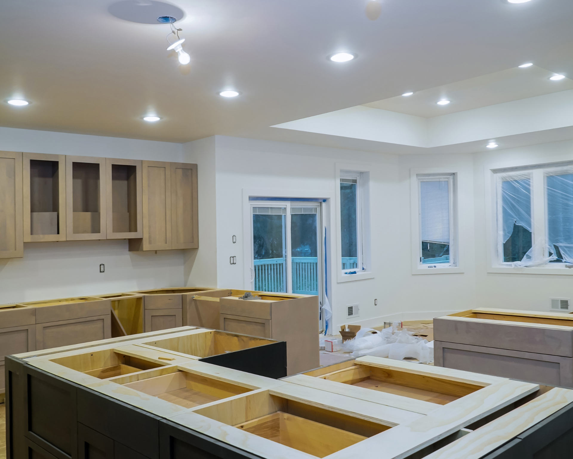 A kitchen under construction with wooden cabinets and white counter tops.