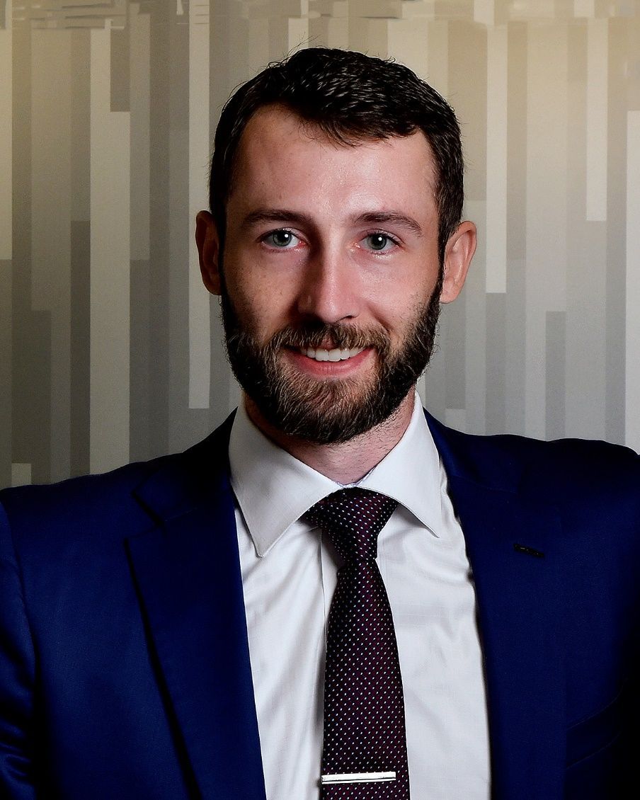 A man with a beard is wearing a blue suit and tie.