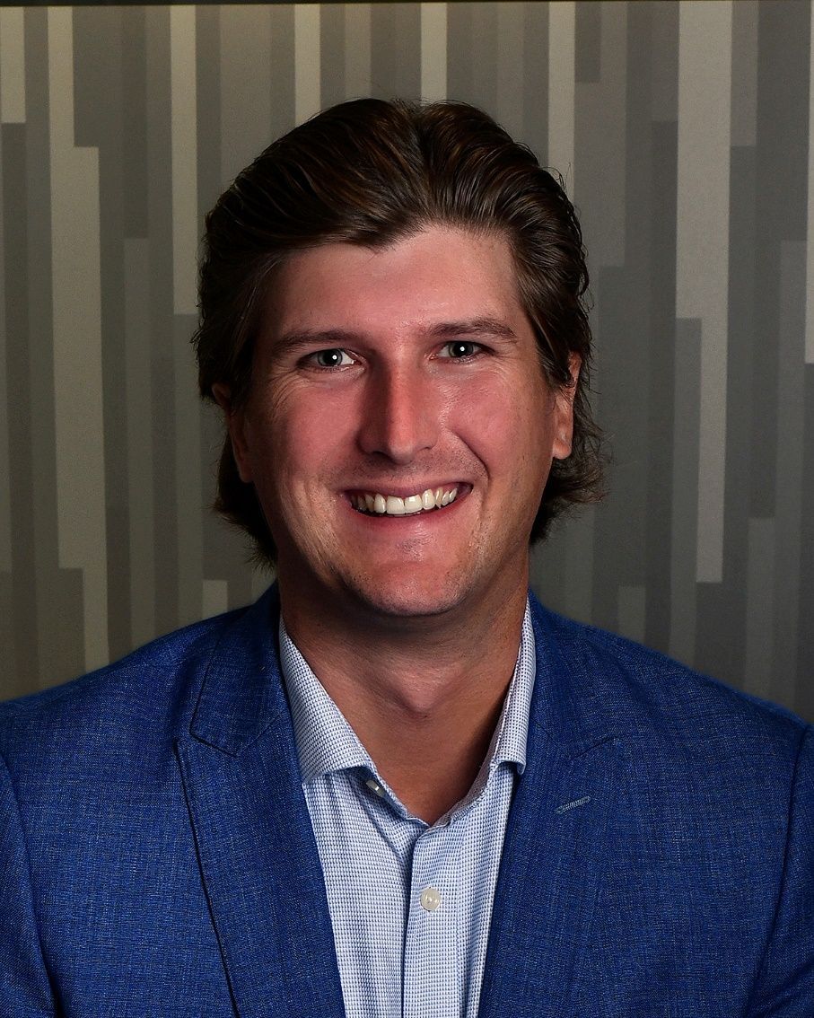 A man in a blue suit and white shirt is smiling for the camera.