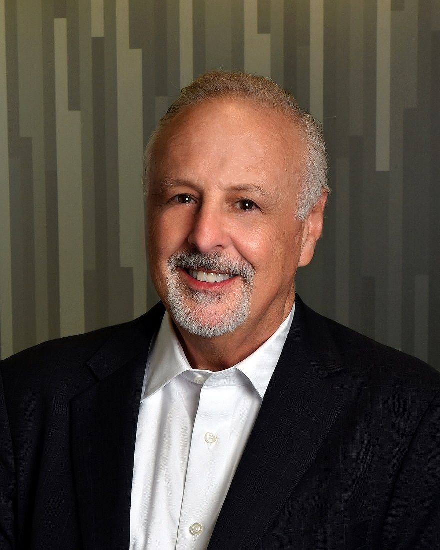 A man in a suit and white shirt is smiling for the camera