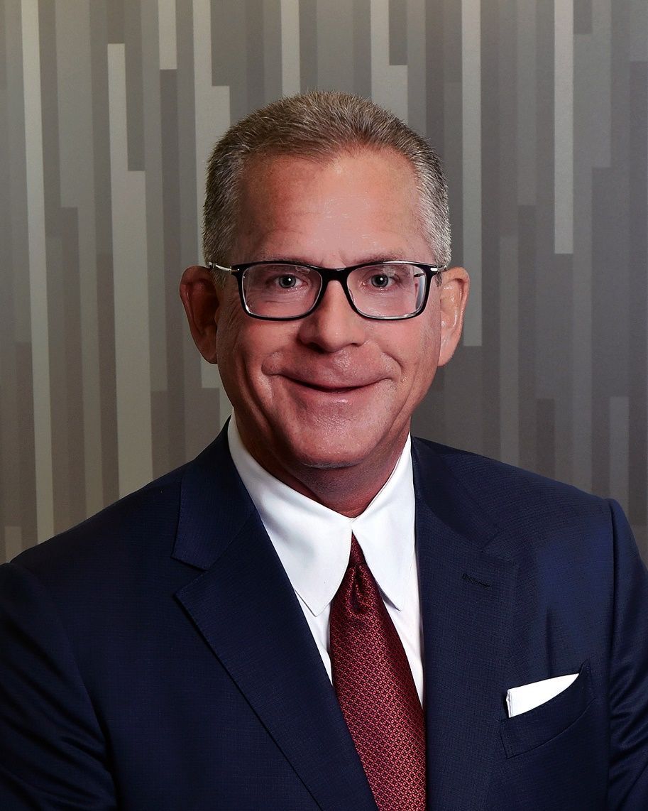 A man in a suit and tie is smiling for the camera