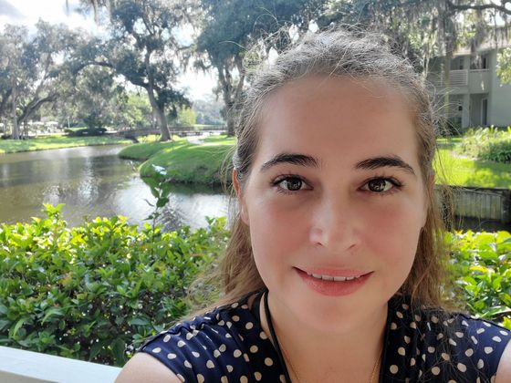 A woman with long black hair is wearing a pink shirt