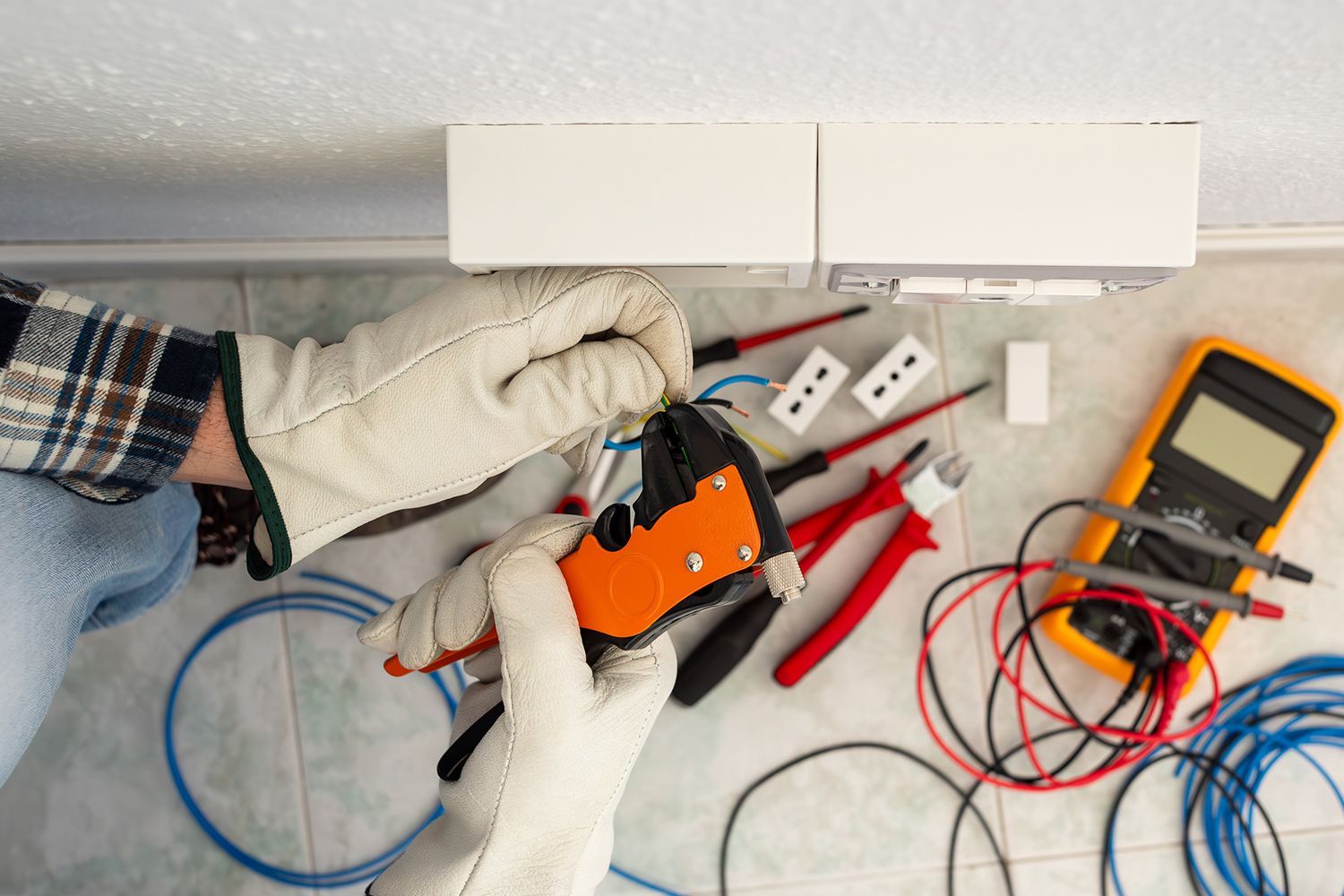 Electrician with wire stripper pliers prepares the electrical cables of an electrical system.
