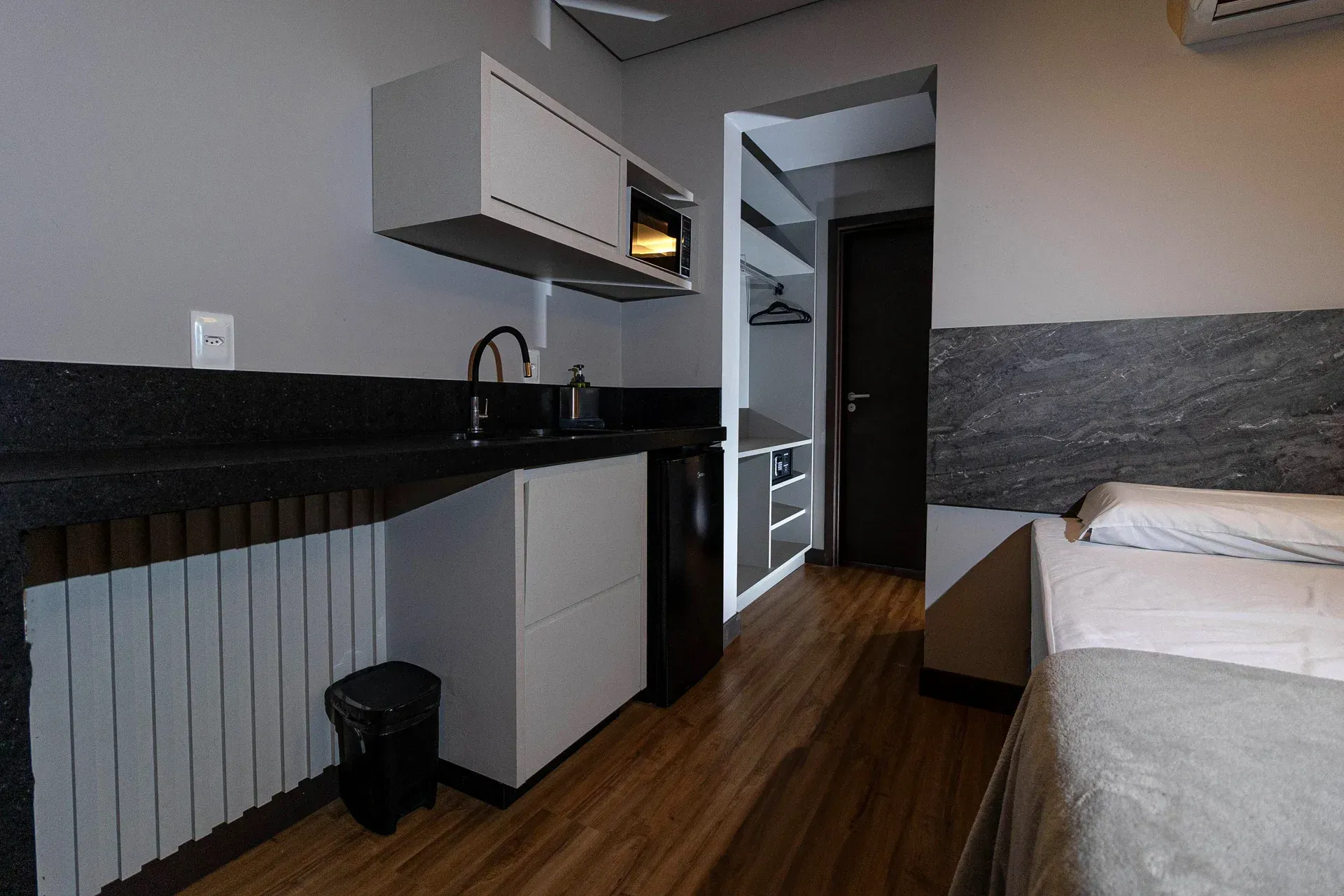 Um quarto de hotel com cama, pia e micro-ondas.