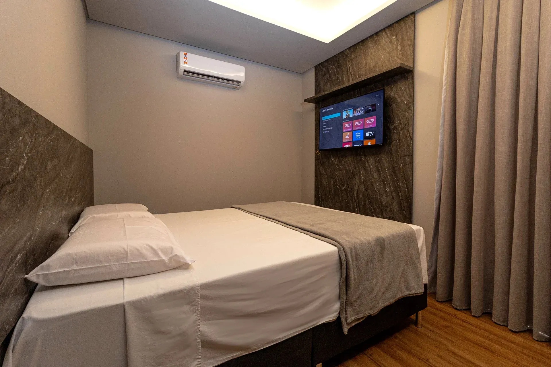 Um quarto de hotel com cama, televisão e ar condicionado.