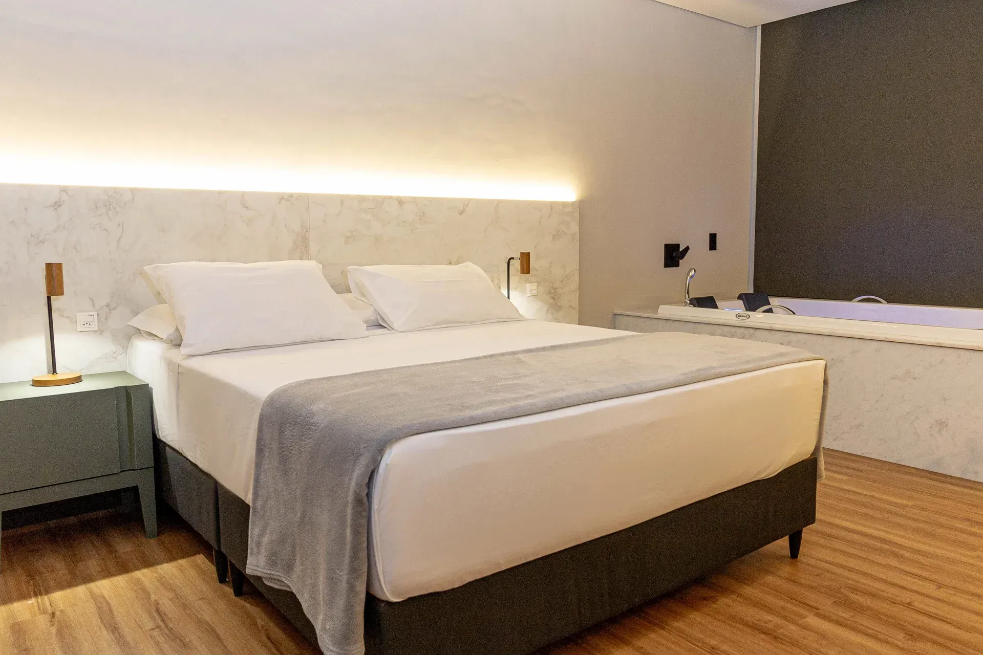 Um quarto de hotel com uma cama king size e uma banheira de hidromassagem.