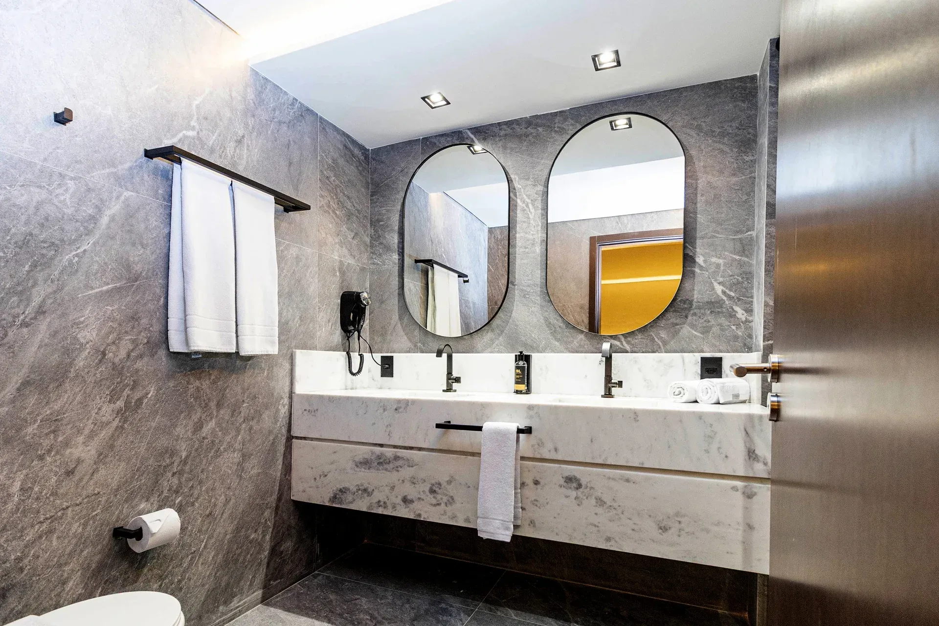 Um banheiro com duas pias, dois espelhos e um vaso sanitário.