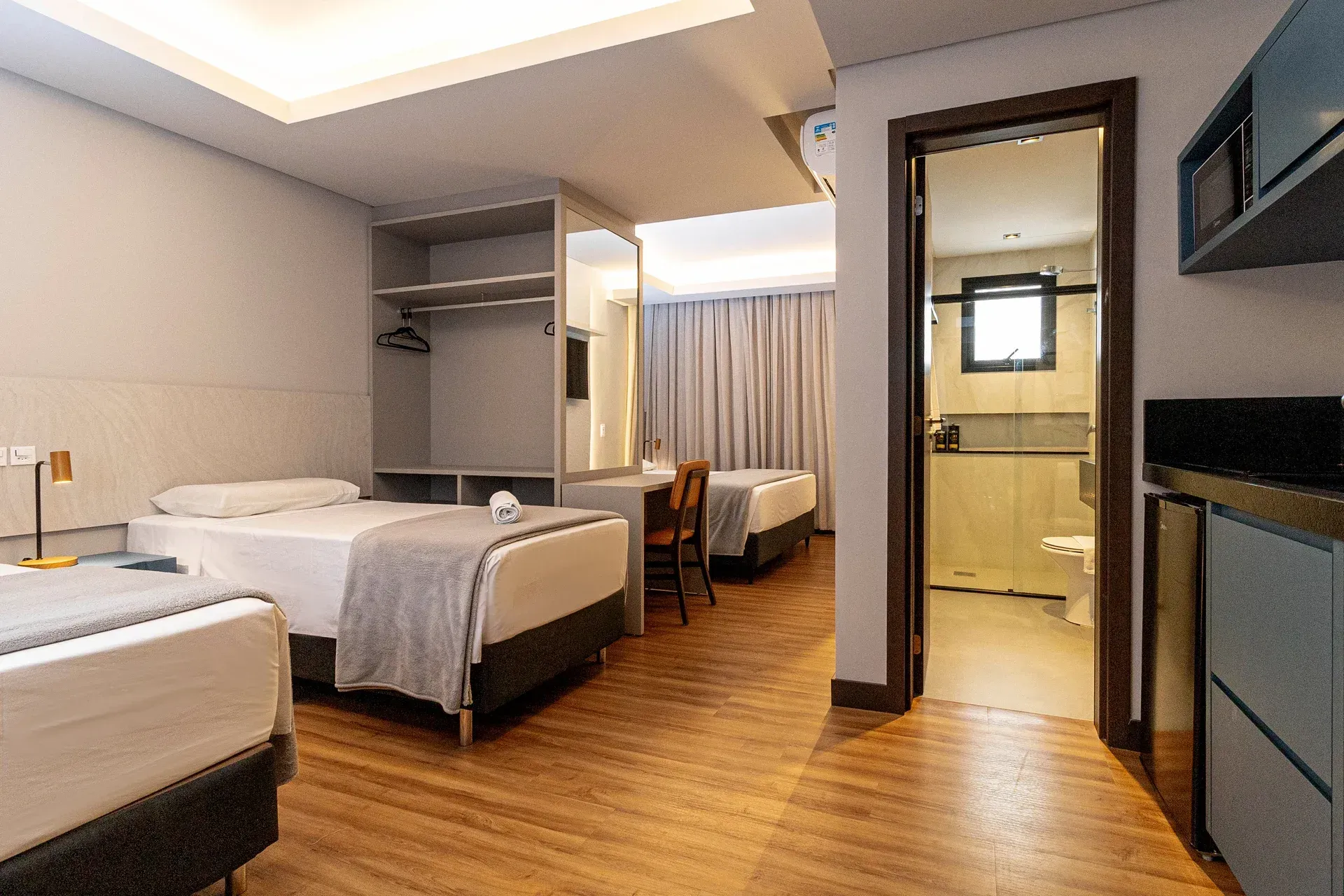 Um quarto de hotel com três camas e um banheiro.