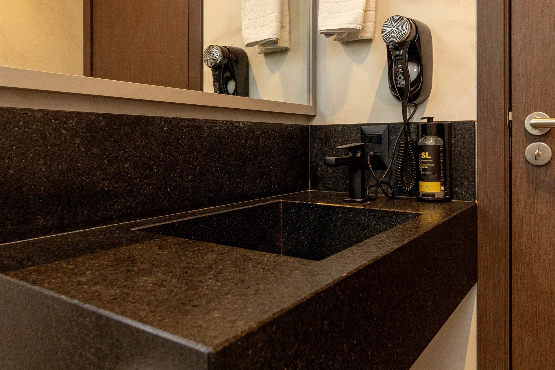 Um banheiro com pia, espelho e secador de cabelo