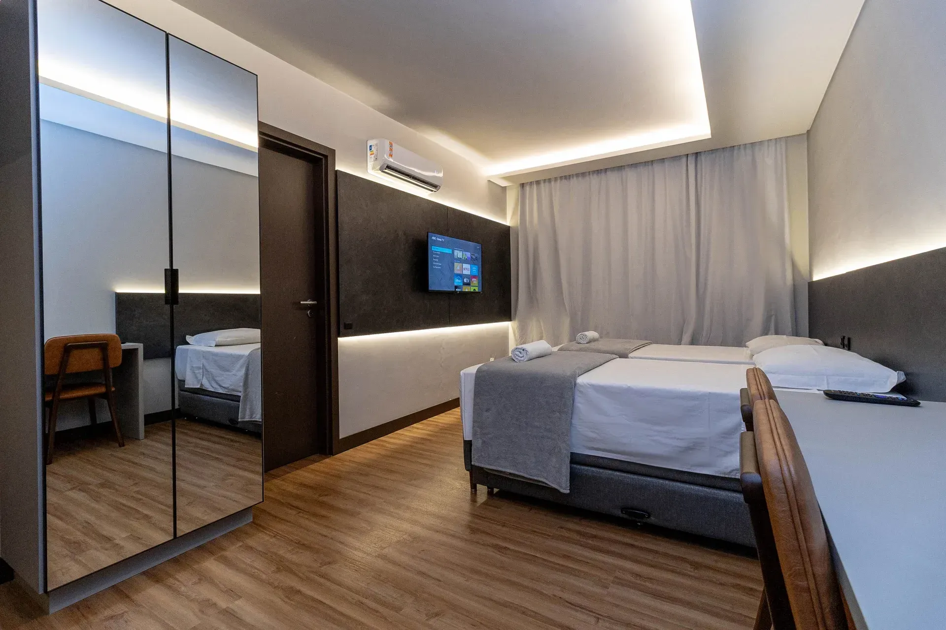 Um quarto de hotel com duas camas, uma escrivaninha e uma televisão.