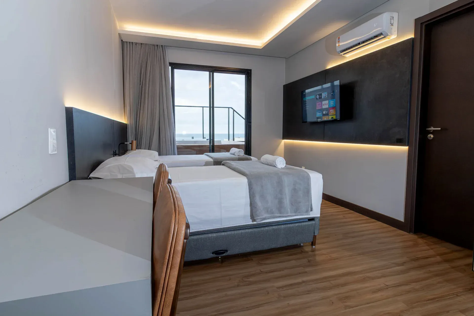 Um quarto de hotel com duas camas, uma escrivaninha e uma televisão.