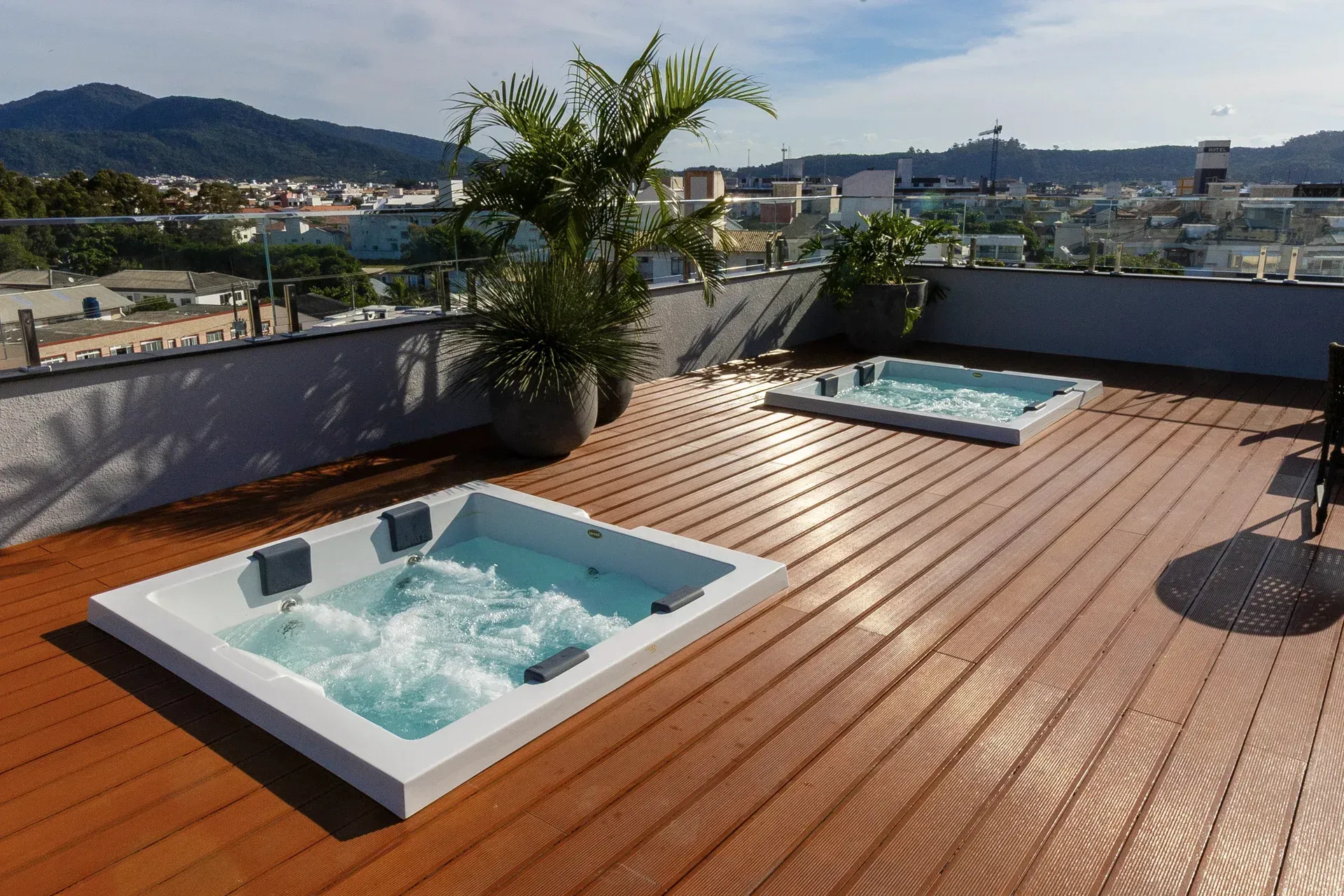 Duas banheiras de hidromassagem em um deck de madeira com montanhas ao fundo