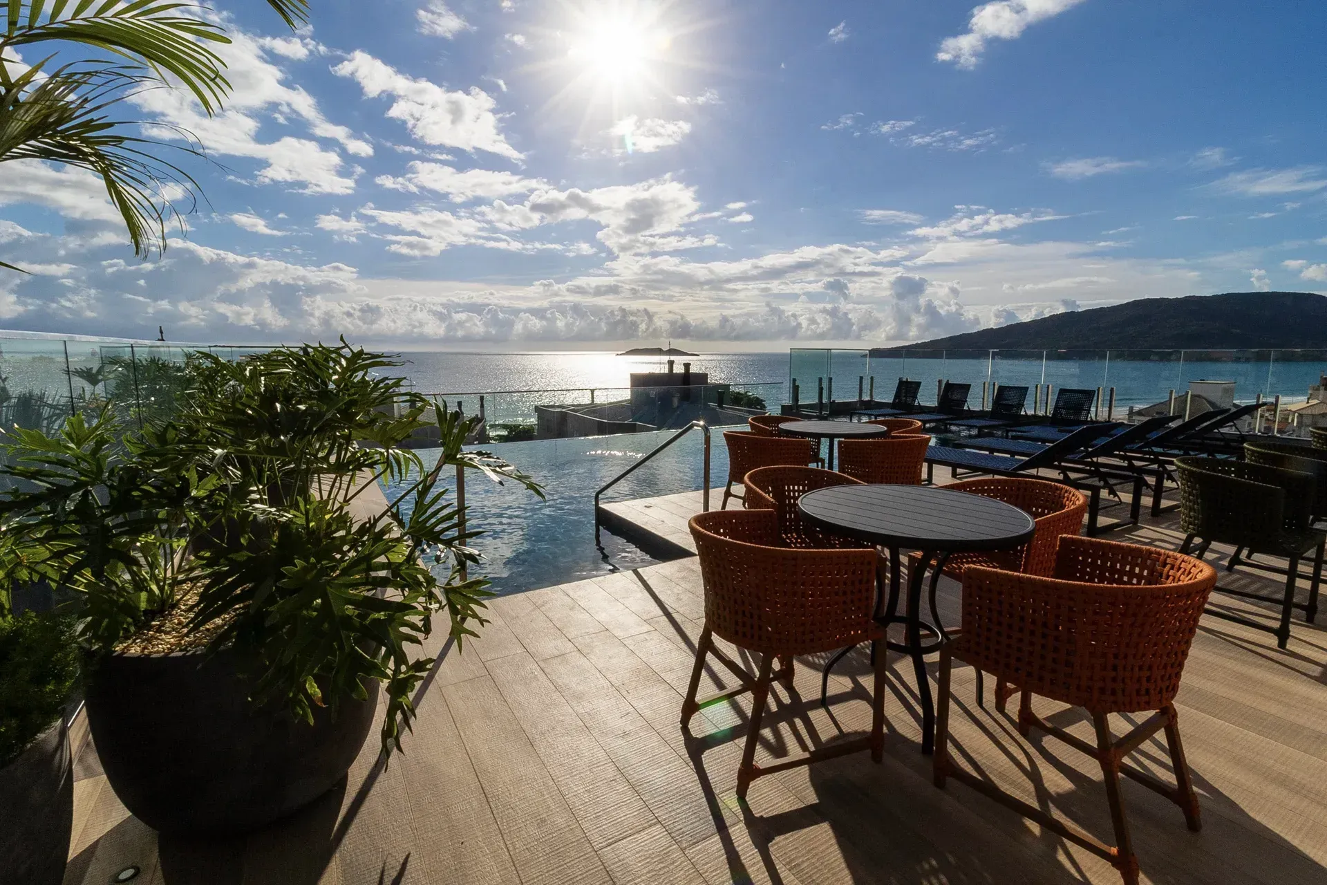 Um pátio com mesas e cadeiras ao lado de uma piscina com vista para o oceano.