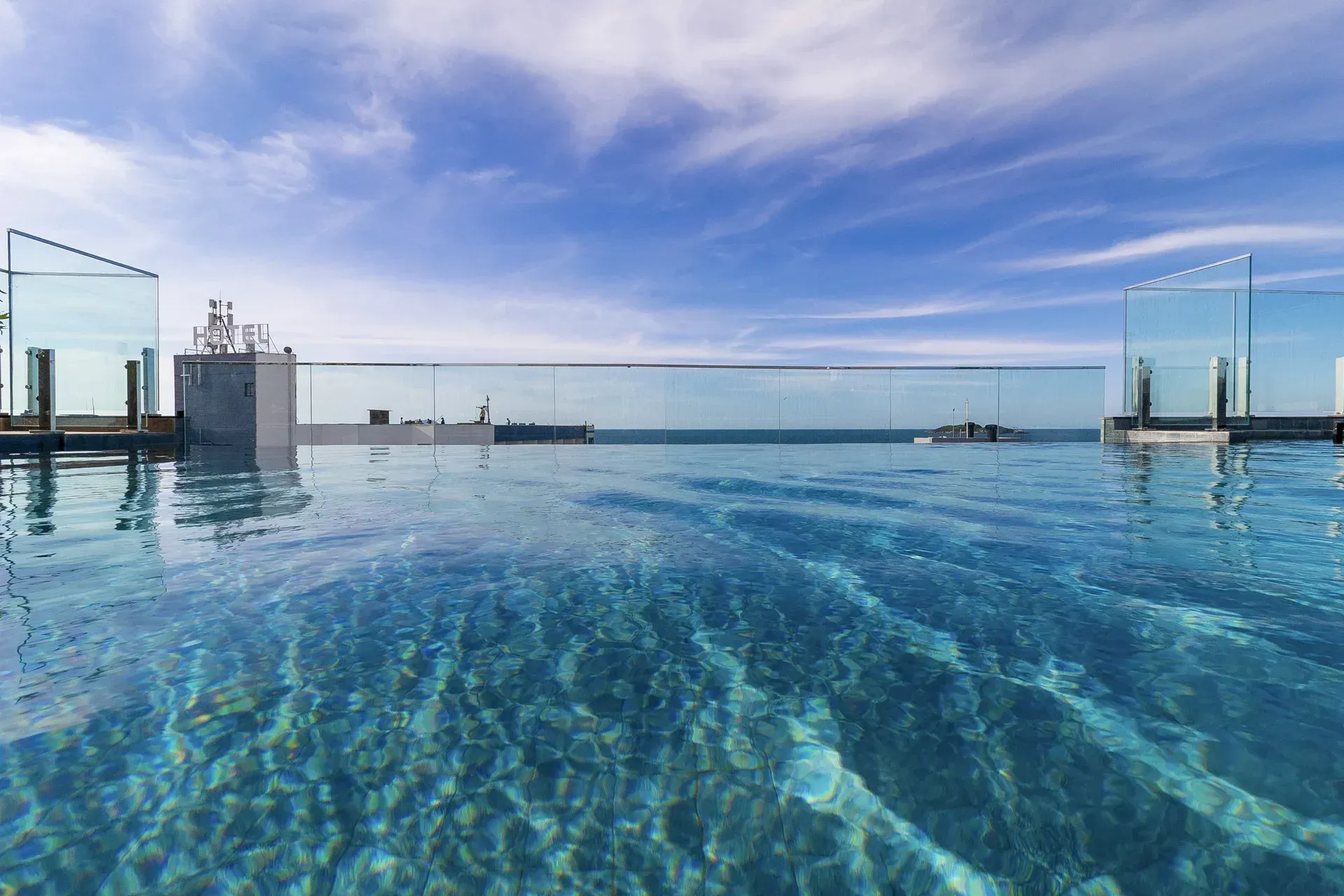Uma grande piscina no topo de um edifício com vista para o oceano.