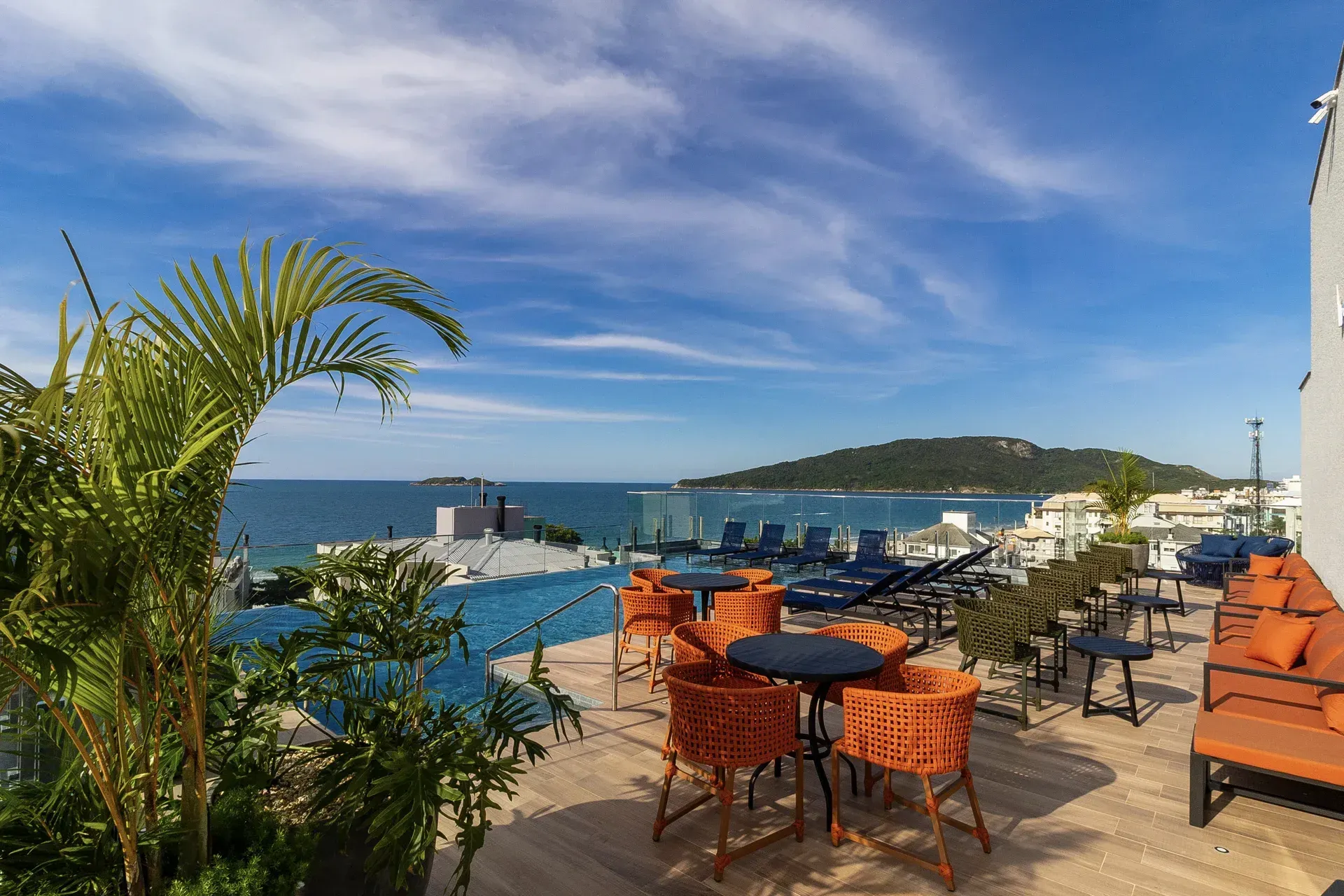 Há mesas e cadeiras no telhado de um prédio com vista para o oceano.