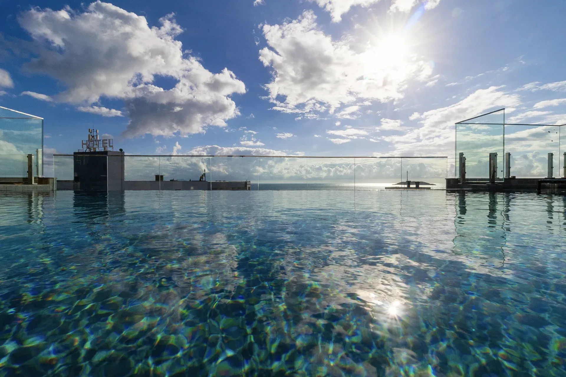 Há uma piscina no telhado de um prédio com vista para o oceano.