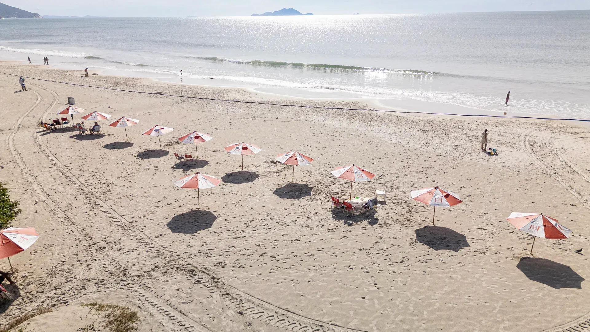 Uma vista aérea de uma praia com guarda-sóis e cadeiras.