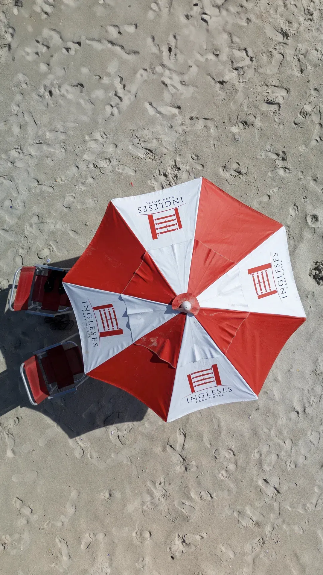 Um guarda-chuva vermelho e branco em uma praia de areia