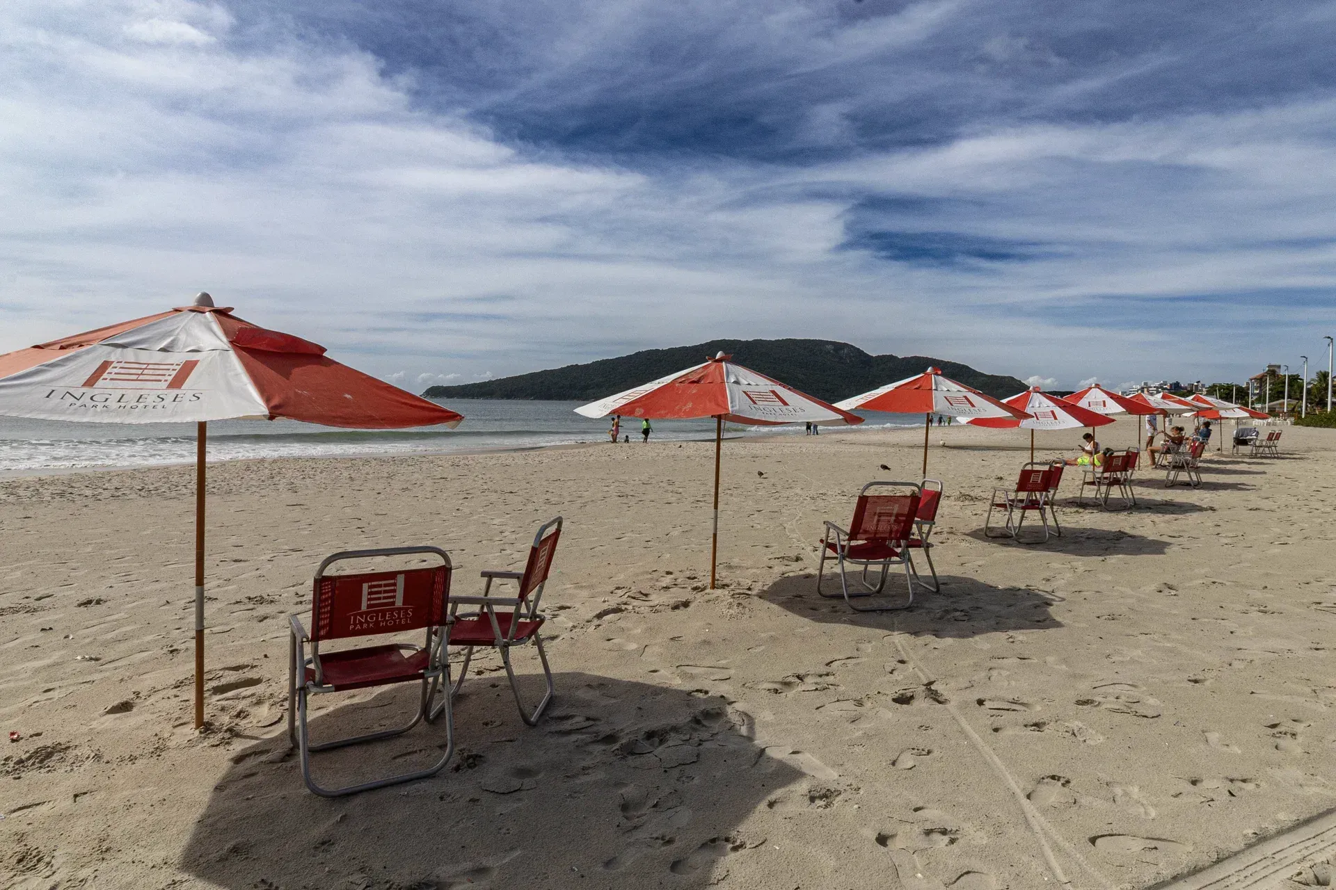 Uma fileira de cadeiras vermelhas e guarda-sóis em uma praia