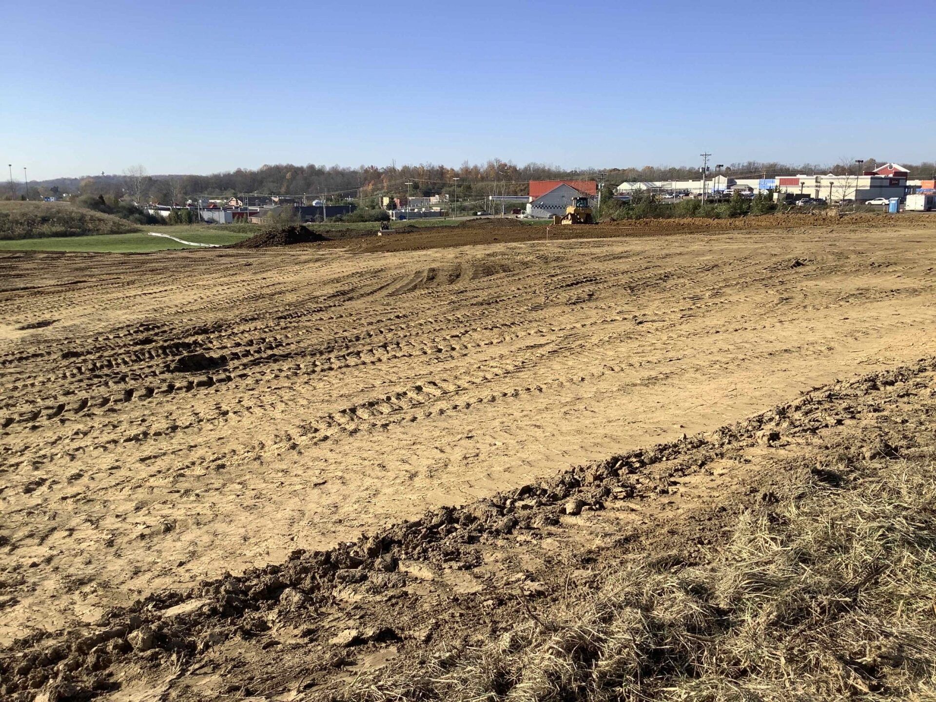 A large dirt field with a tractor in the background.