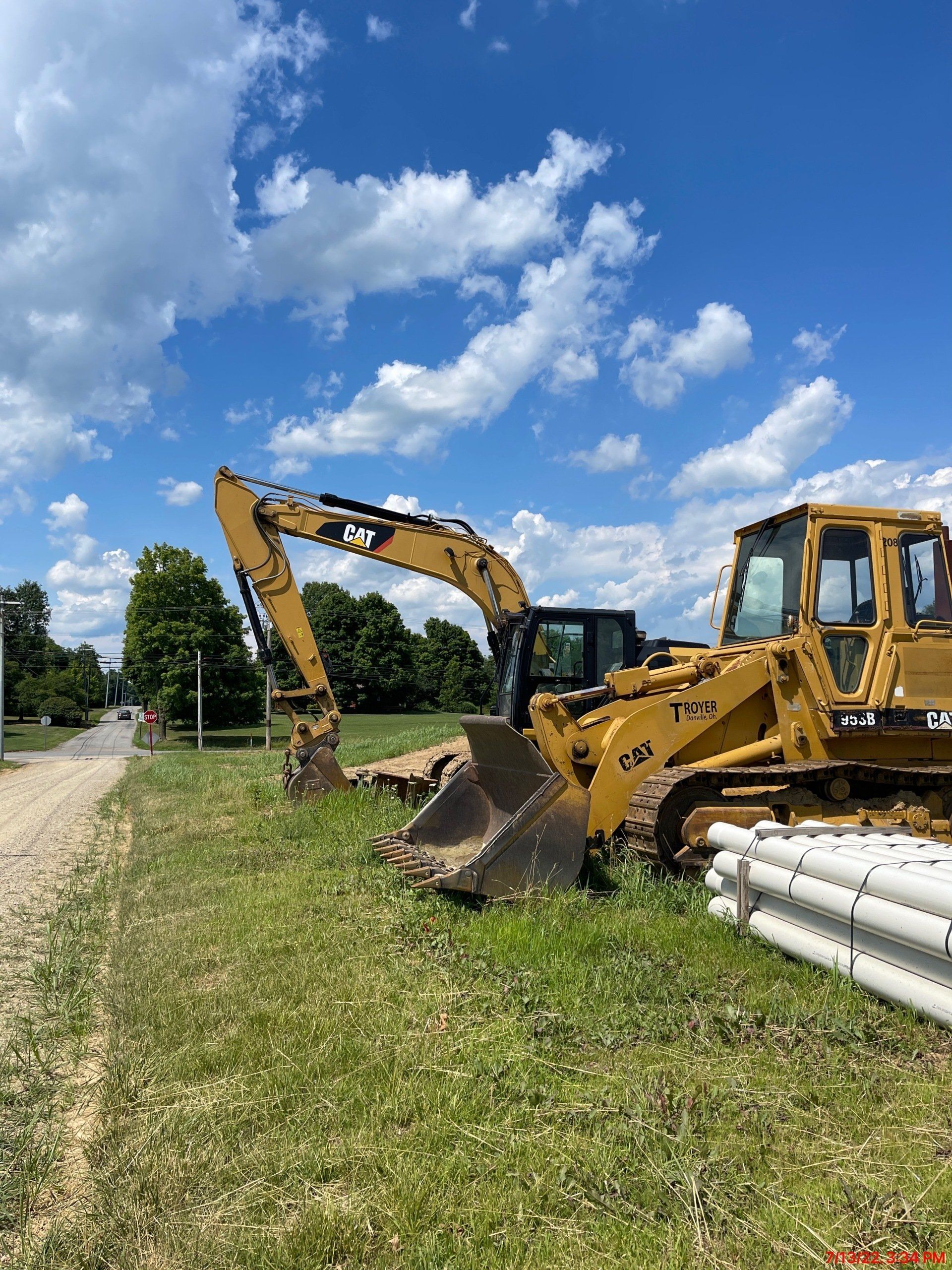 A bulldozer and an excavator are parked in a grassy field.