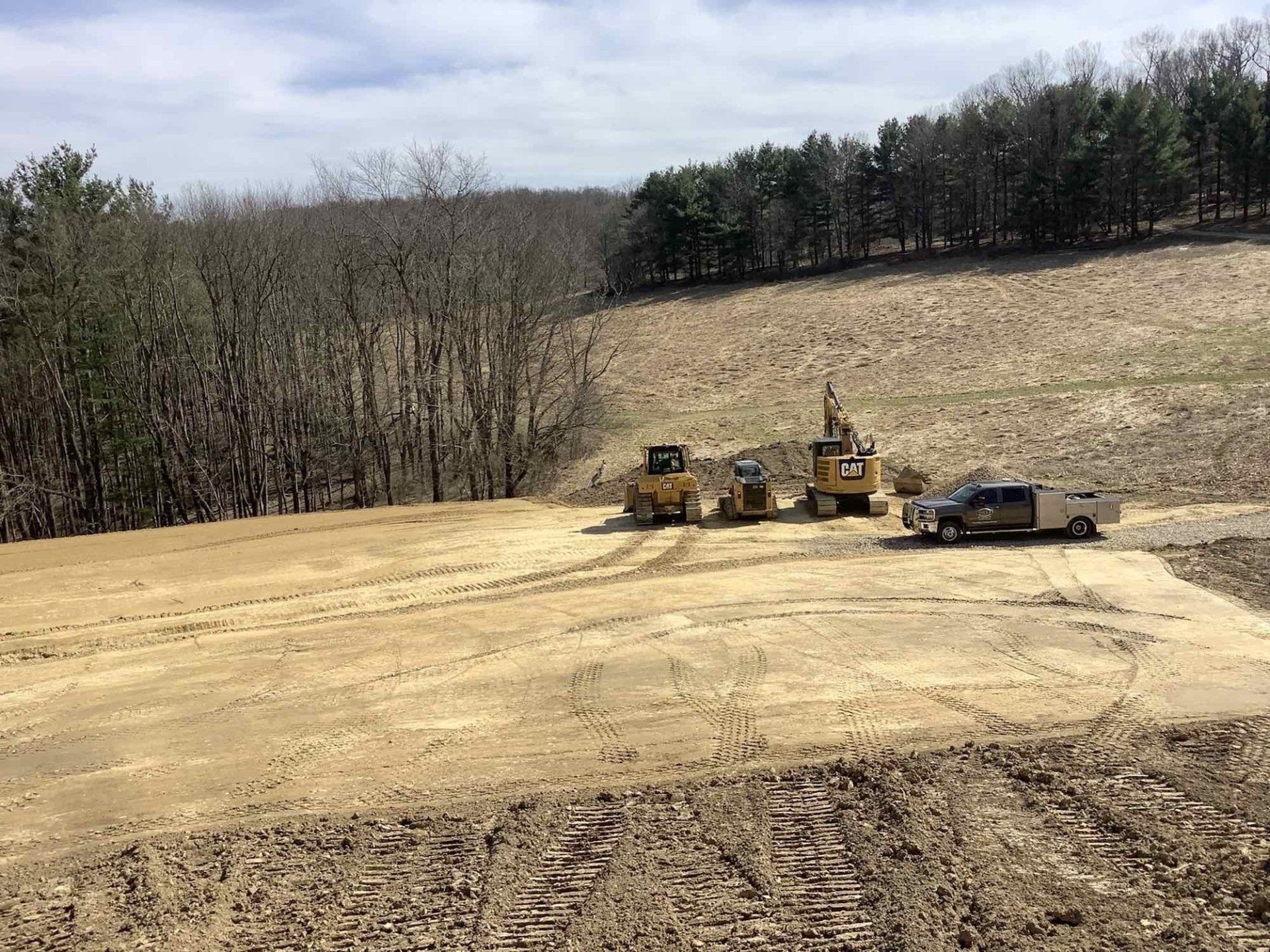 A group of construction vehicles are working on a dirt field.