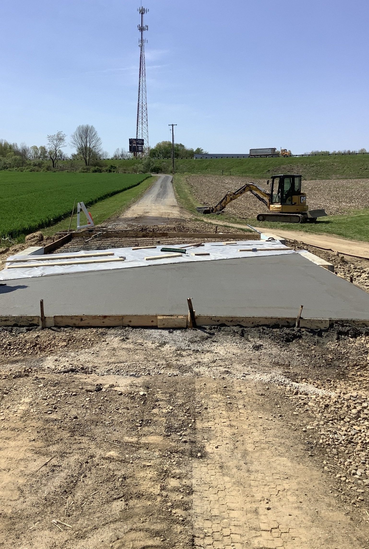 A concrete slab is being poured in a dirt field with a bulldozer in the background.