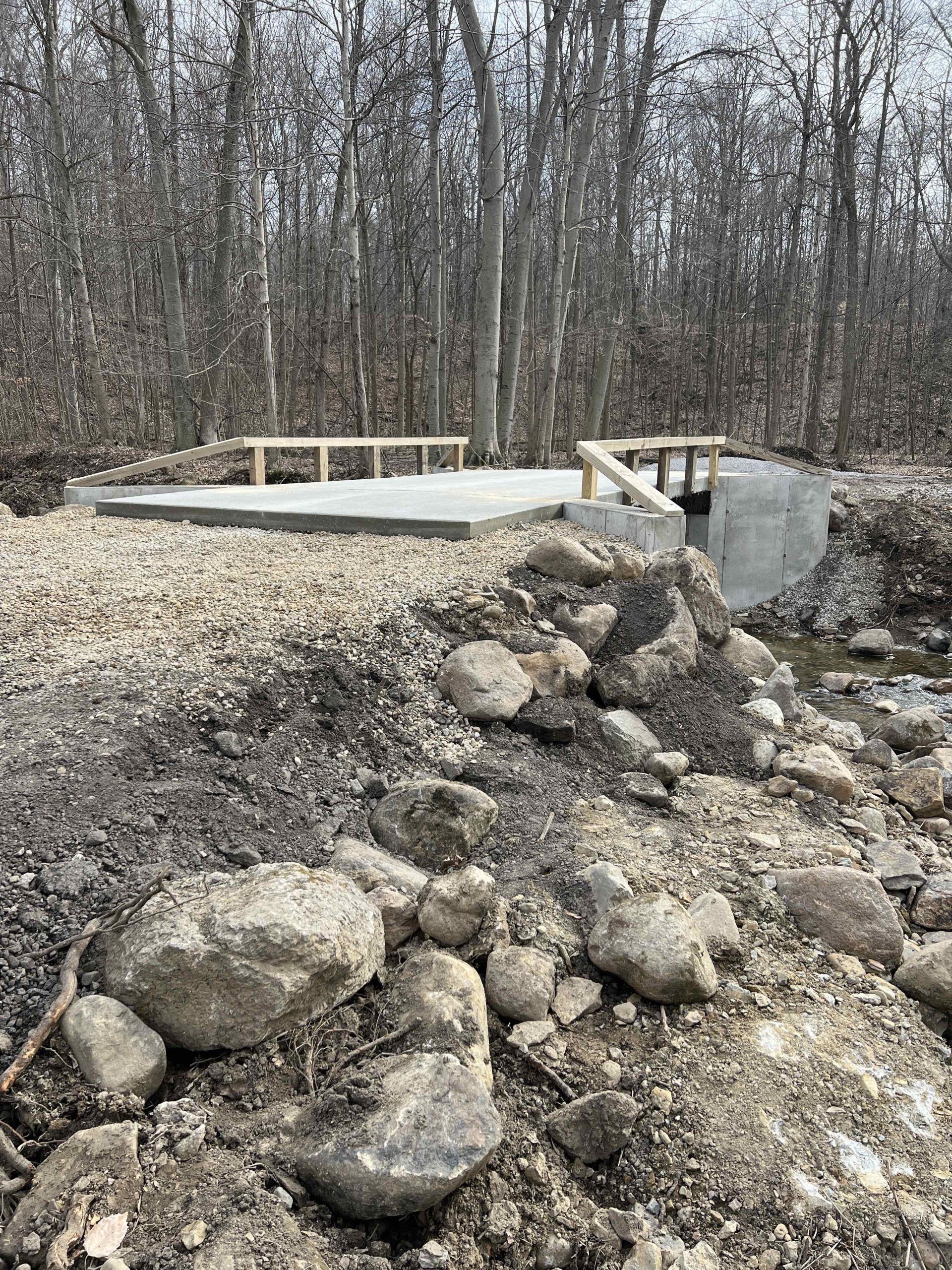 A bridge is being built over a stream in the woods.
