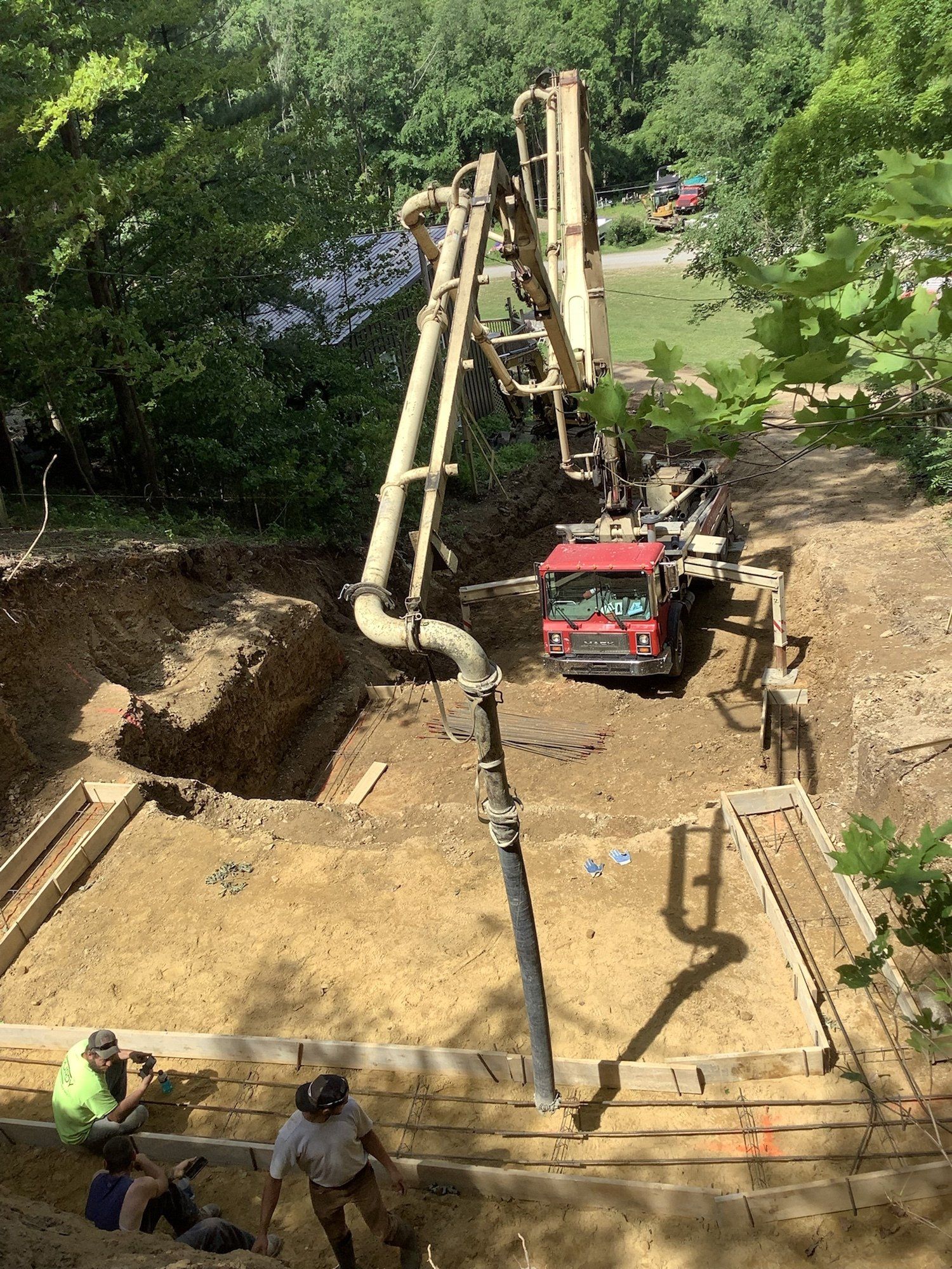 A concrete pump is pumping concrete into a hole in the ground.