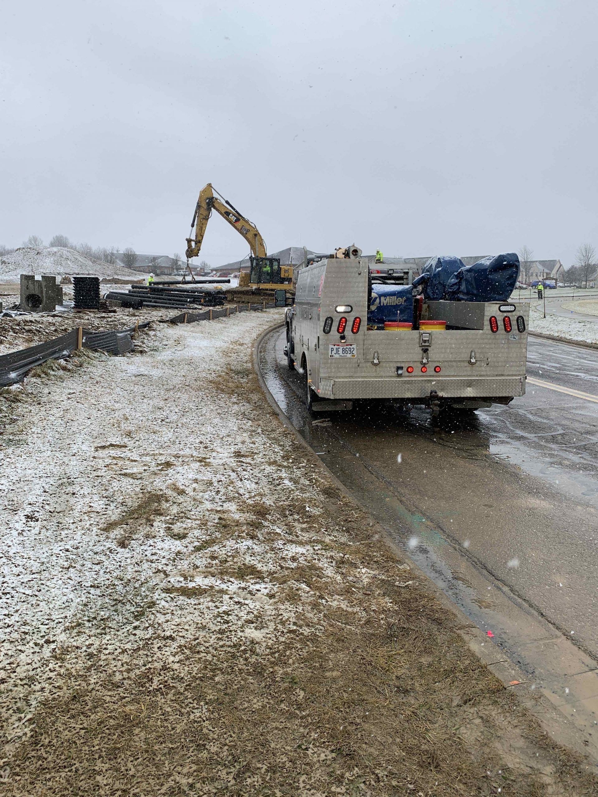 A truck is driving down a snowy road next to a construction site.