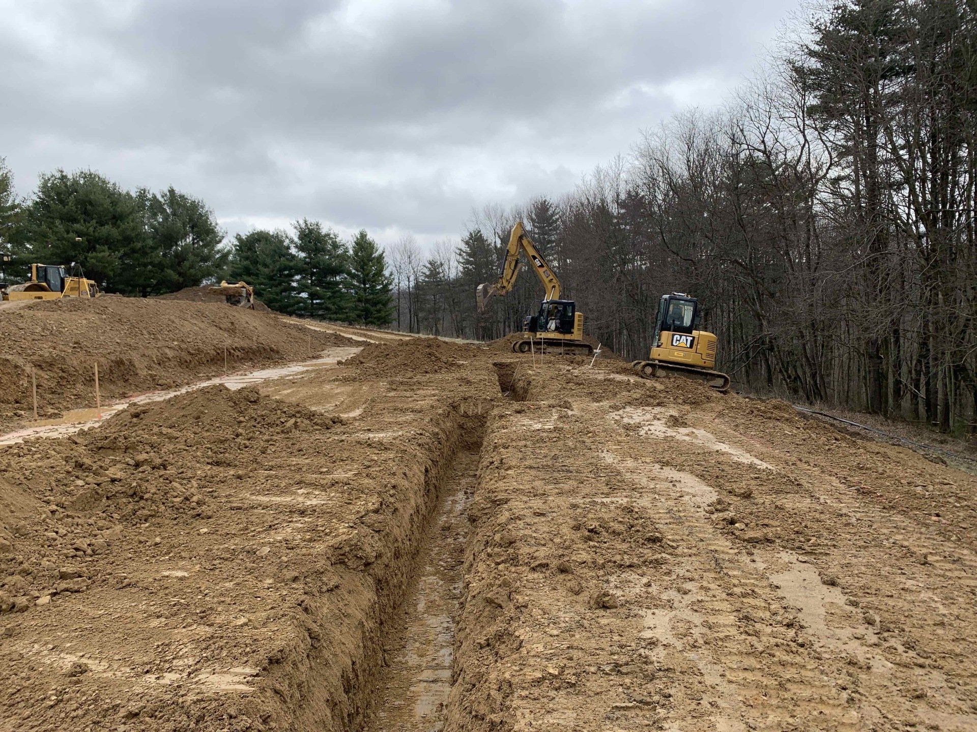 A construction site with a lot of dirt and trees in the background.
