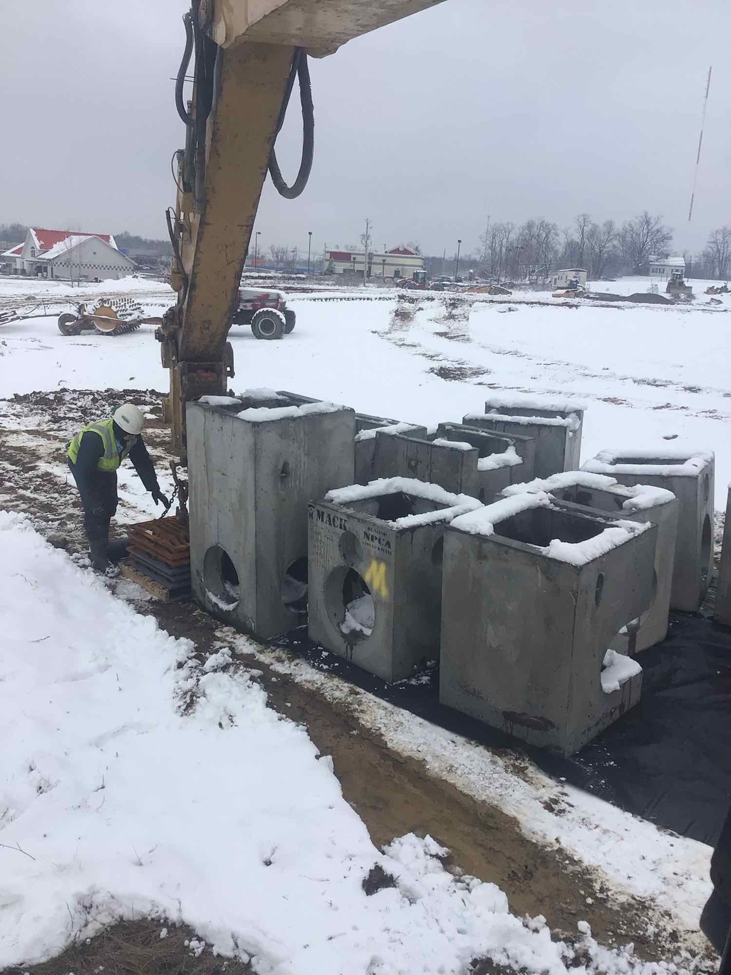 A man is standing next to a pile of concrete blocks in the snow.