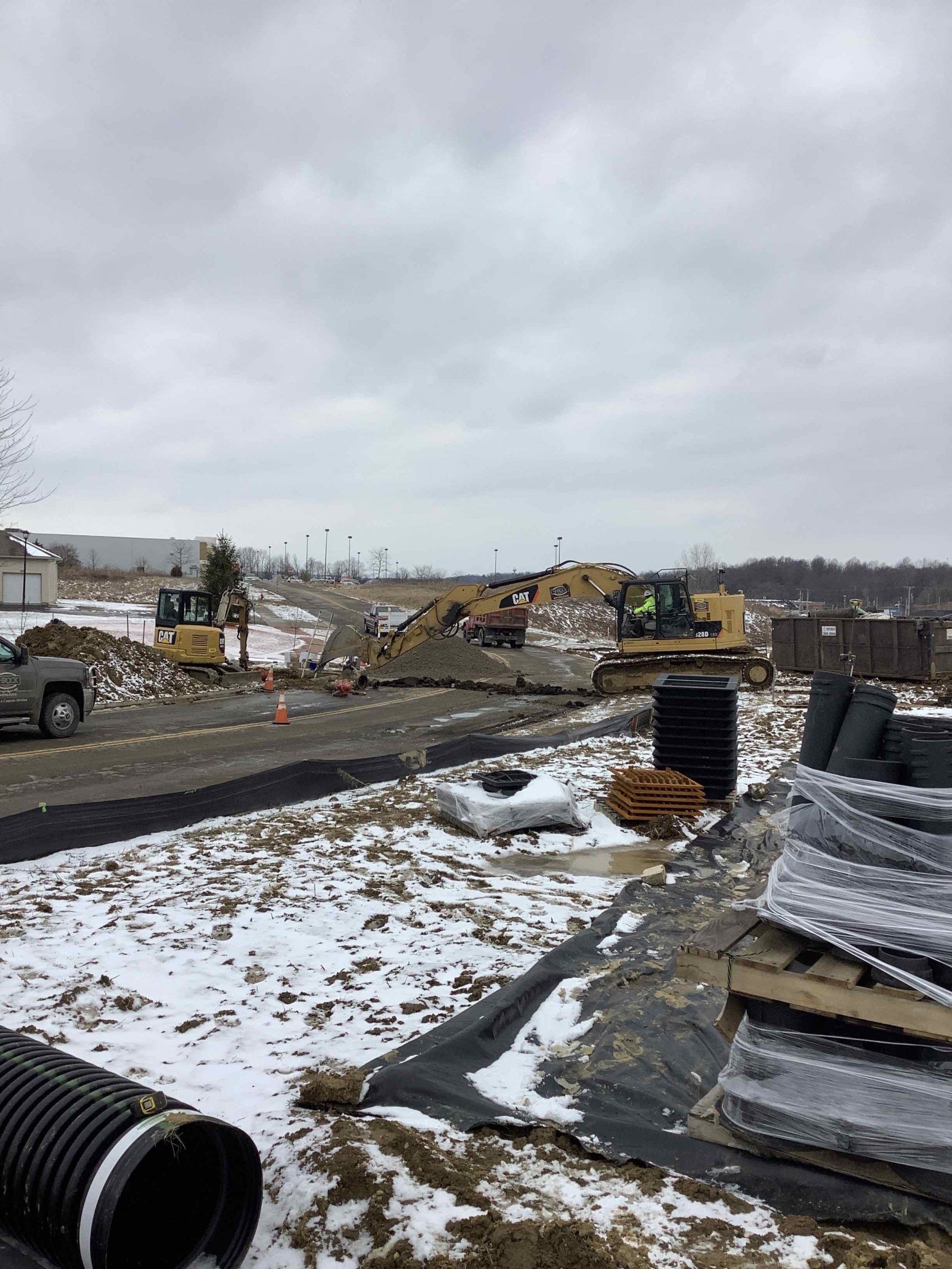 A construction site with a lot of machinery and pipes in the snow.