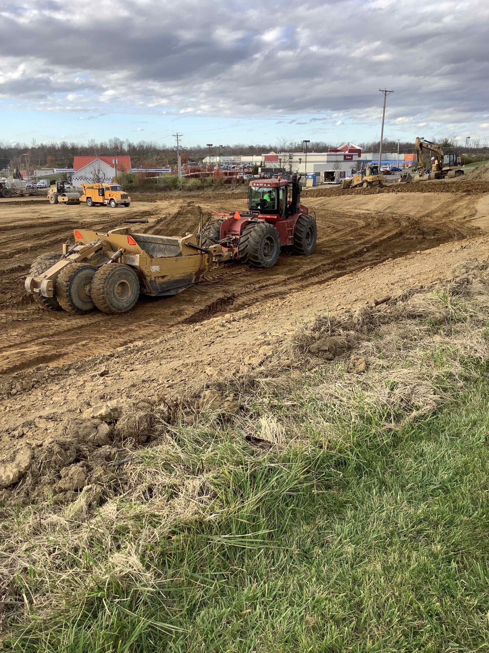 A tractor and a bulldozer are working on a dirt road.