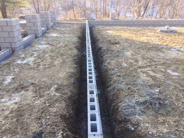 A concrete block wall is being built in the dirt