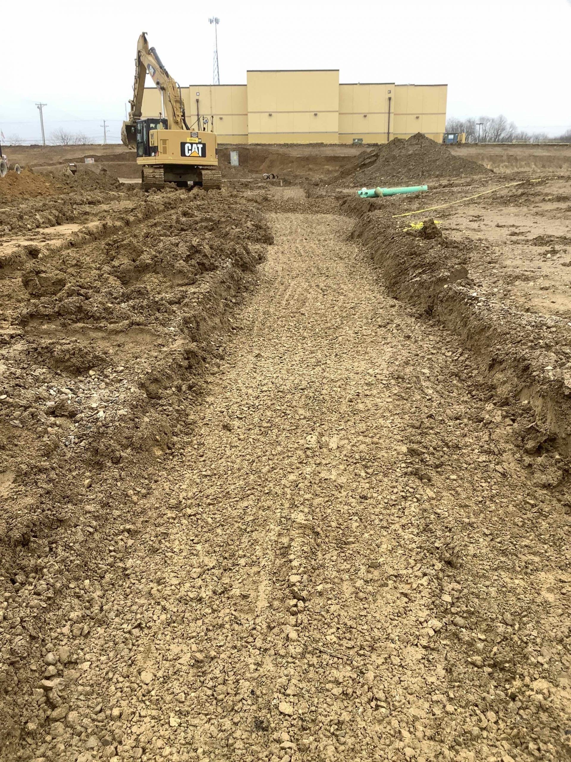 A bulldozer is digging a hole in the dirt in front of a building.