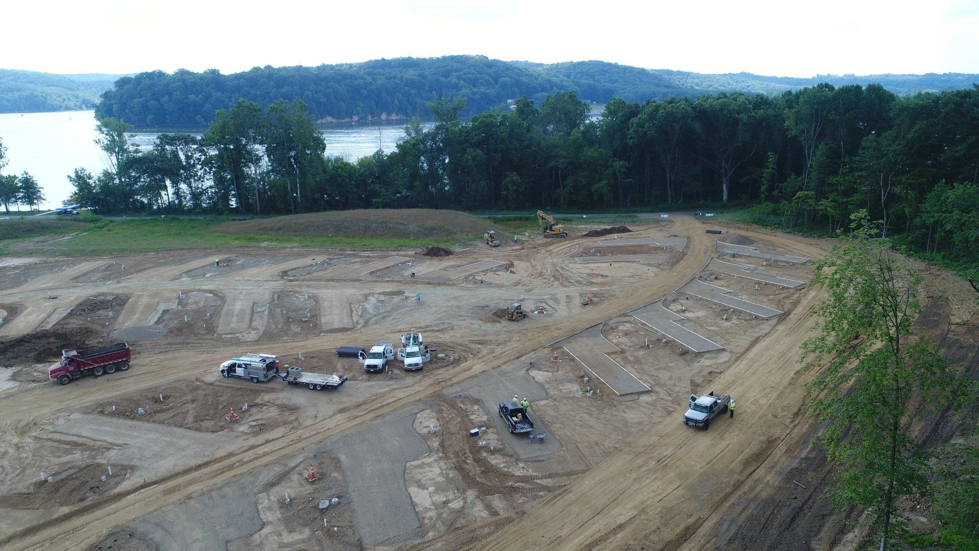 An aerial view of a construction site with a lake in the background