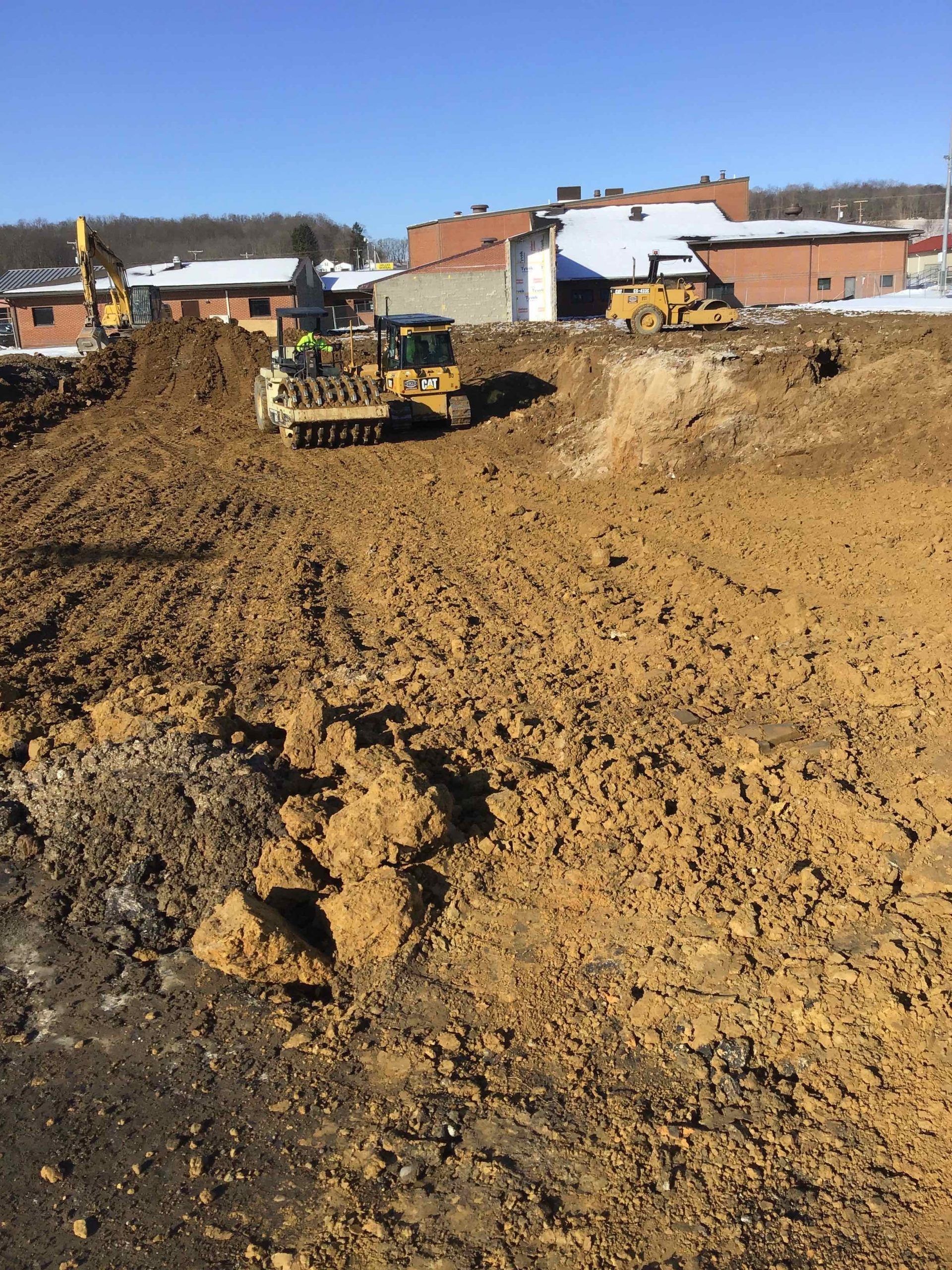 A couple of bulldozers are working on a dirt field.