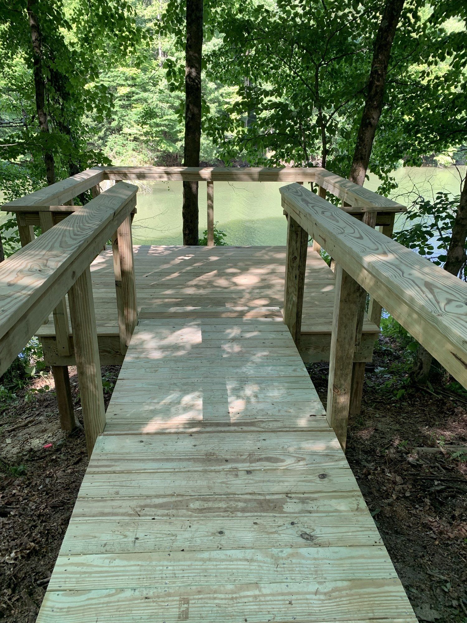 A wooden dock leading to a lake in the woods.