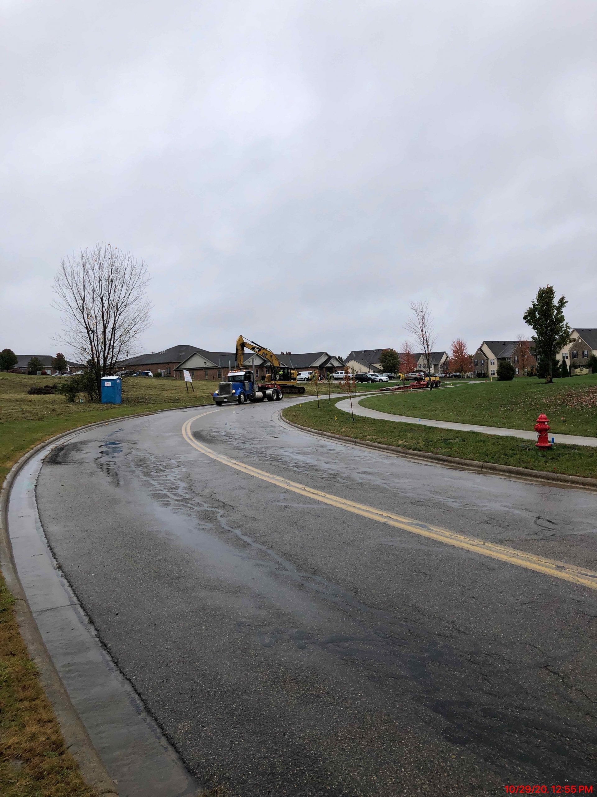 A road with a fire hydrant on the side of it in a residential area.