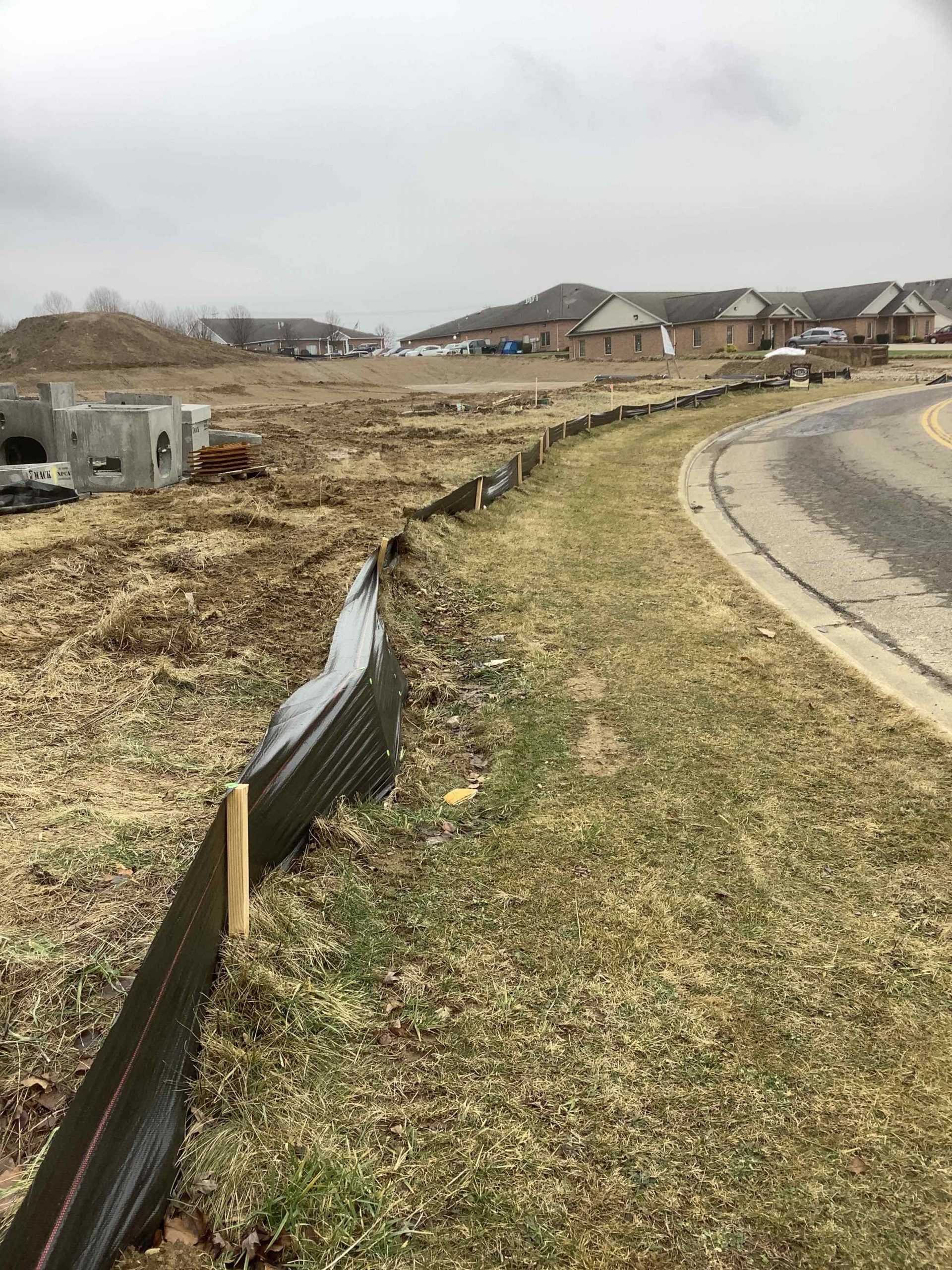 A fence is surrounding a grassy field next to a road.