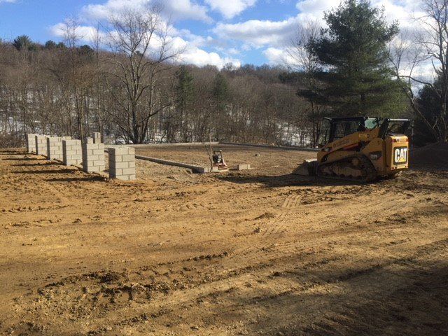A yellow cat bulldozer is driving through a dirt field.