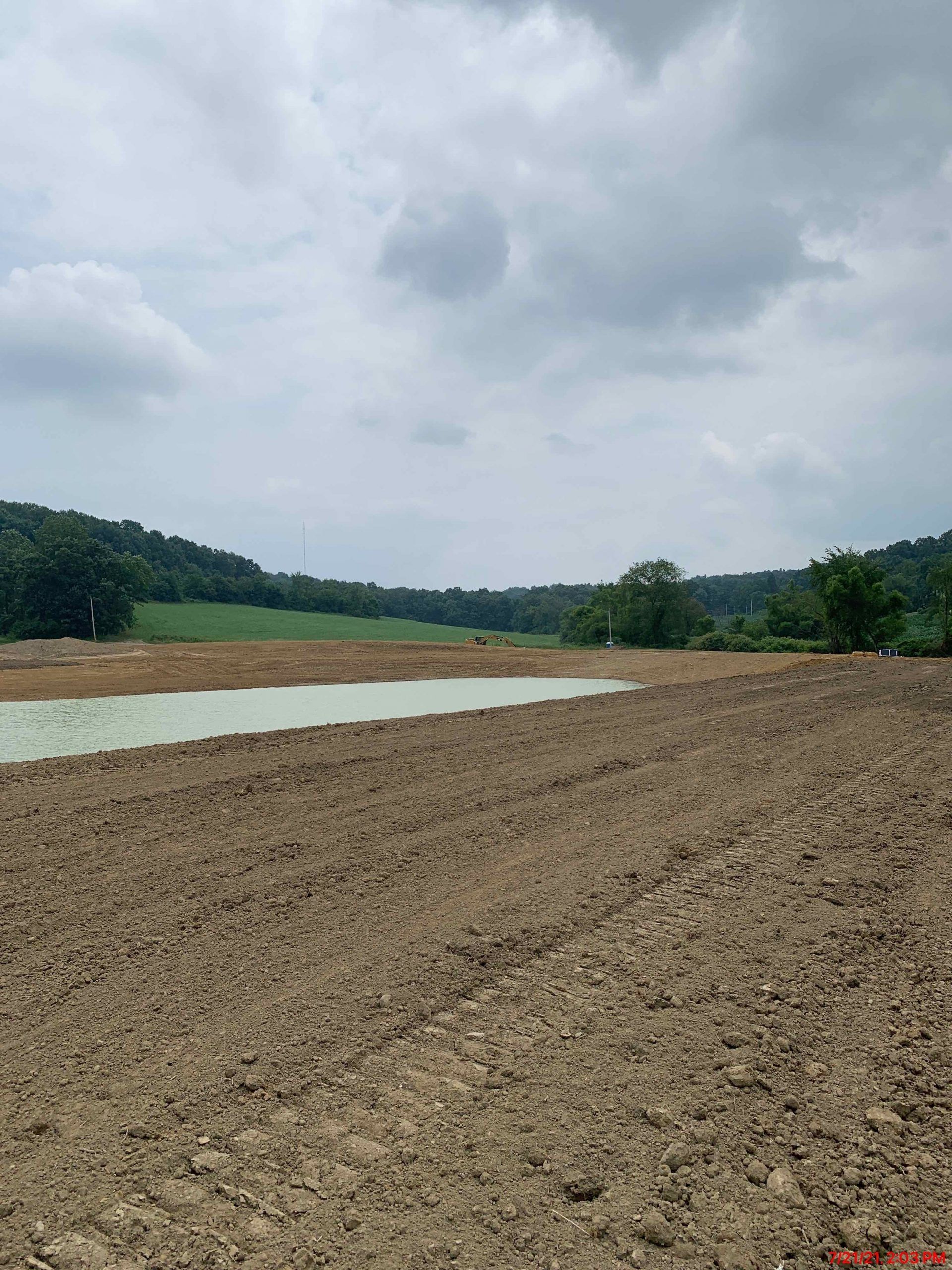 There is a small pond in the middle of a dirt field.
