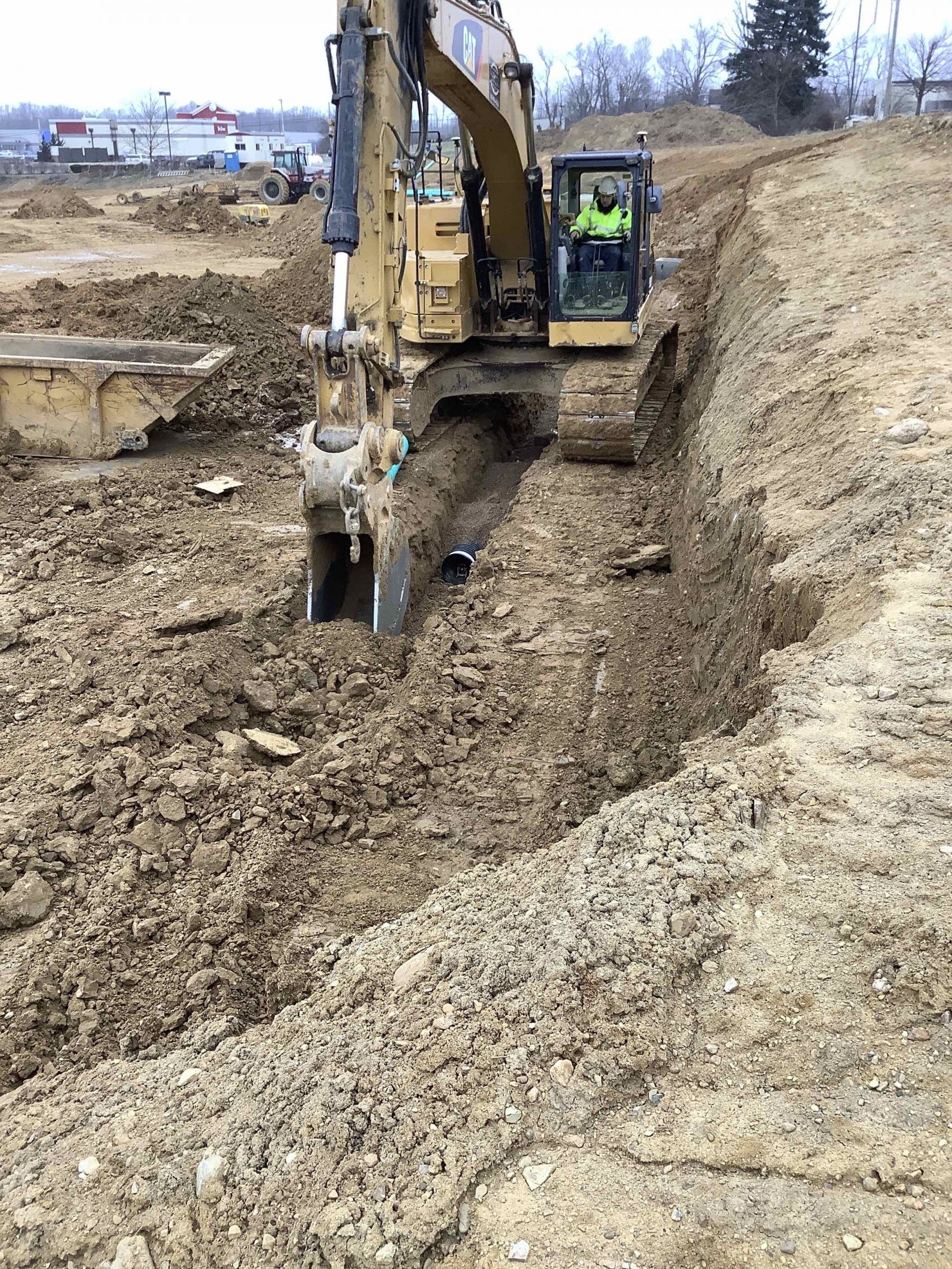 A man is driving a bulldozer in a dirt field.