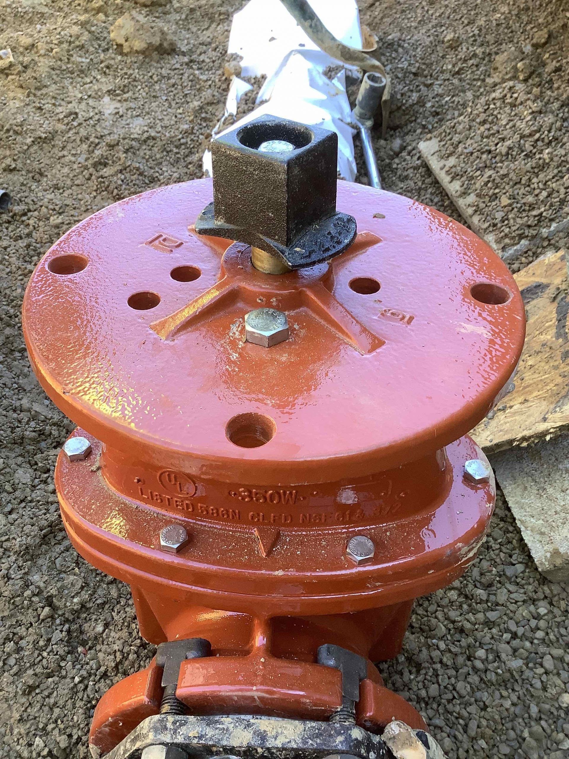 A close up of a red pipe with a brick on top of it.