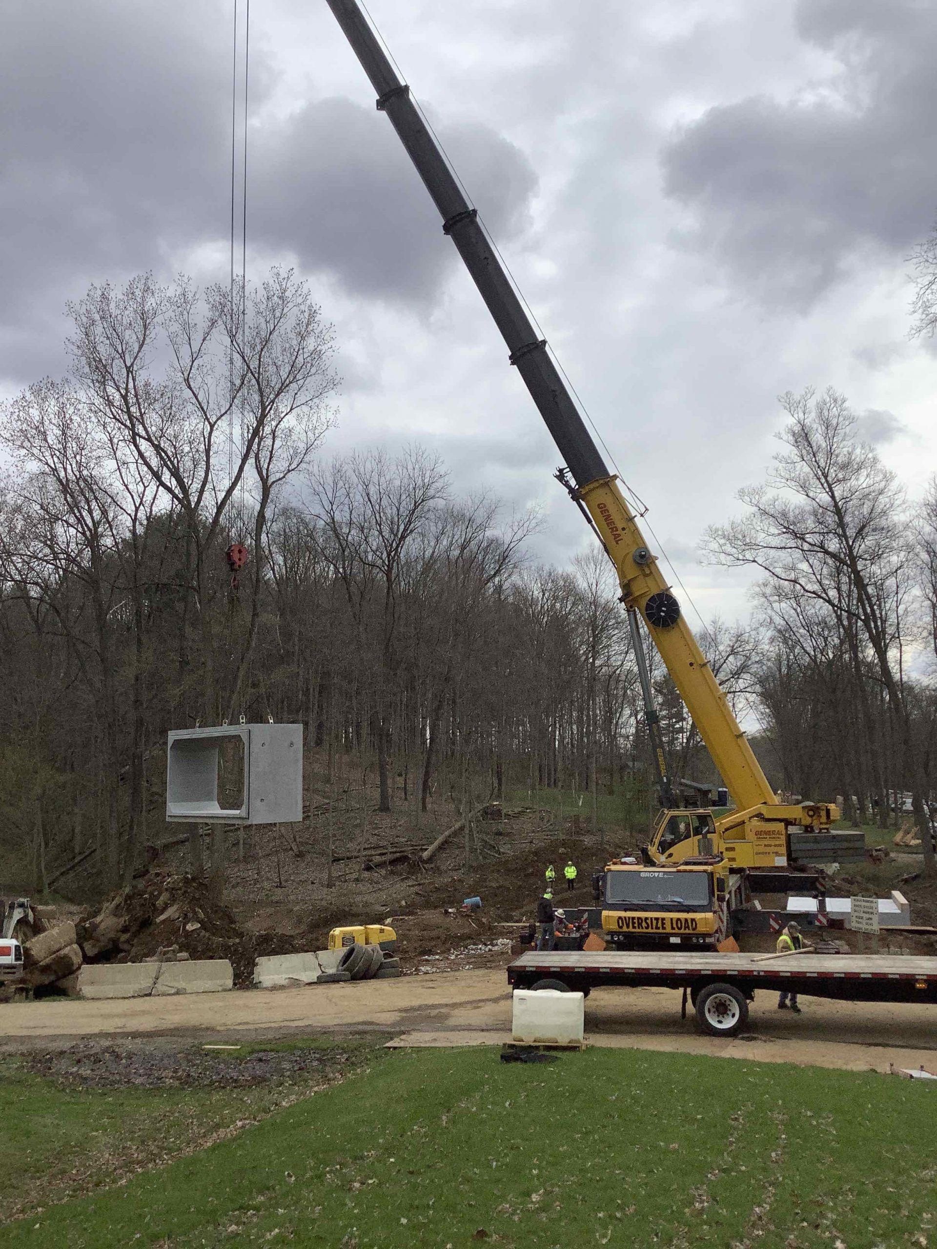 A large yellow crane is lifting a box in the air.