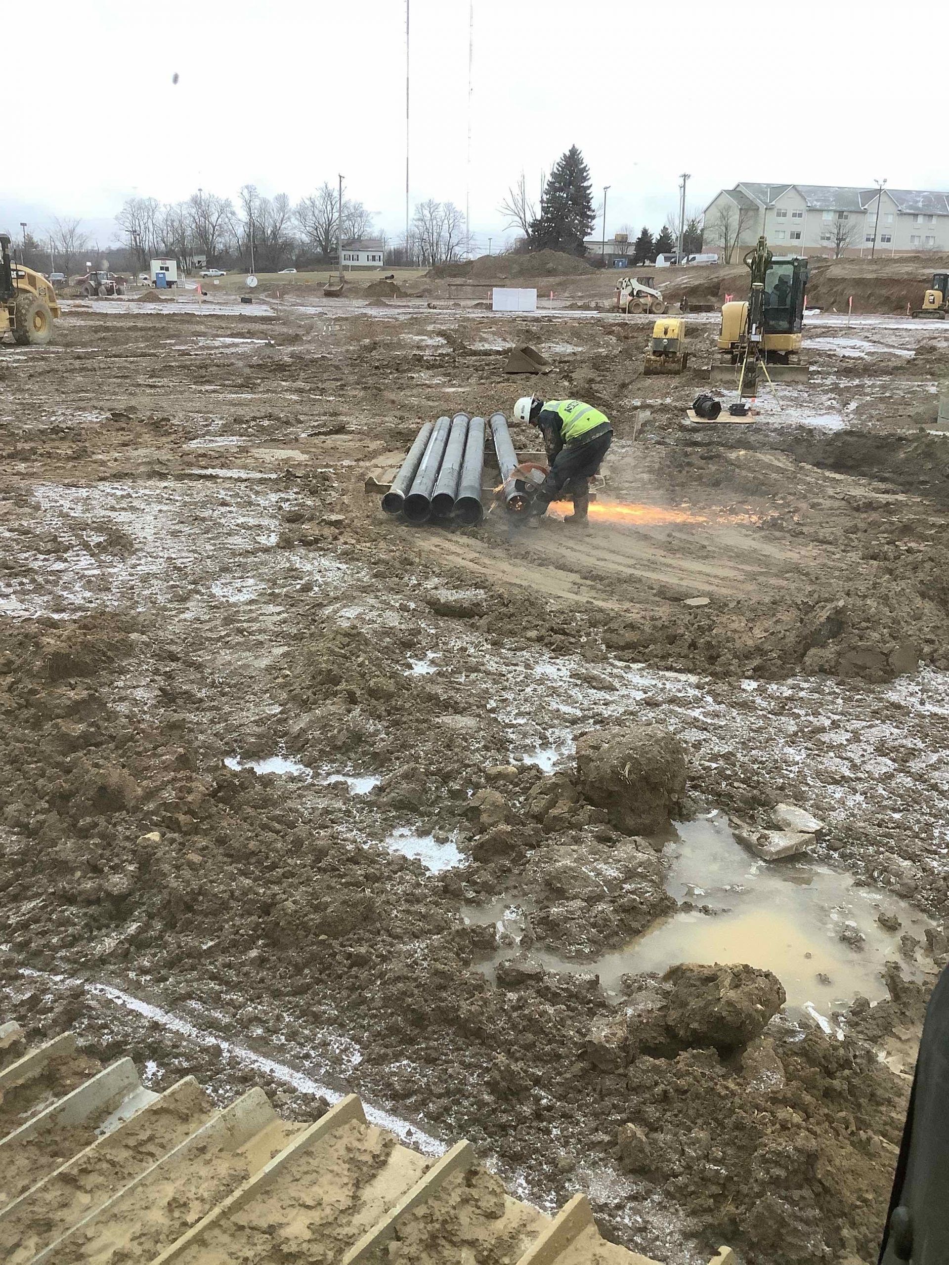 A construction worker is working in a muddy field.